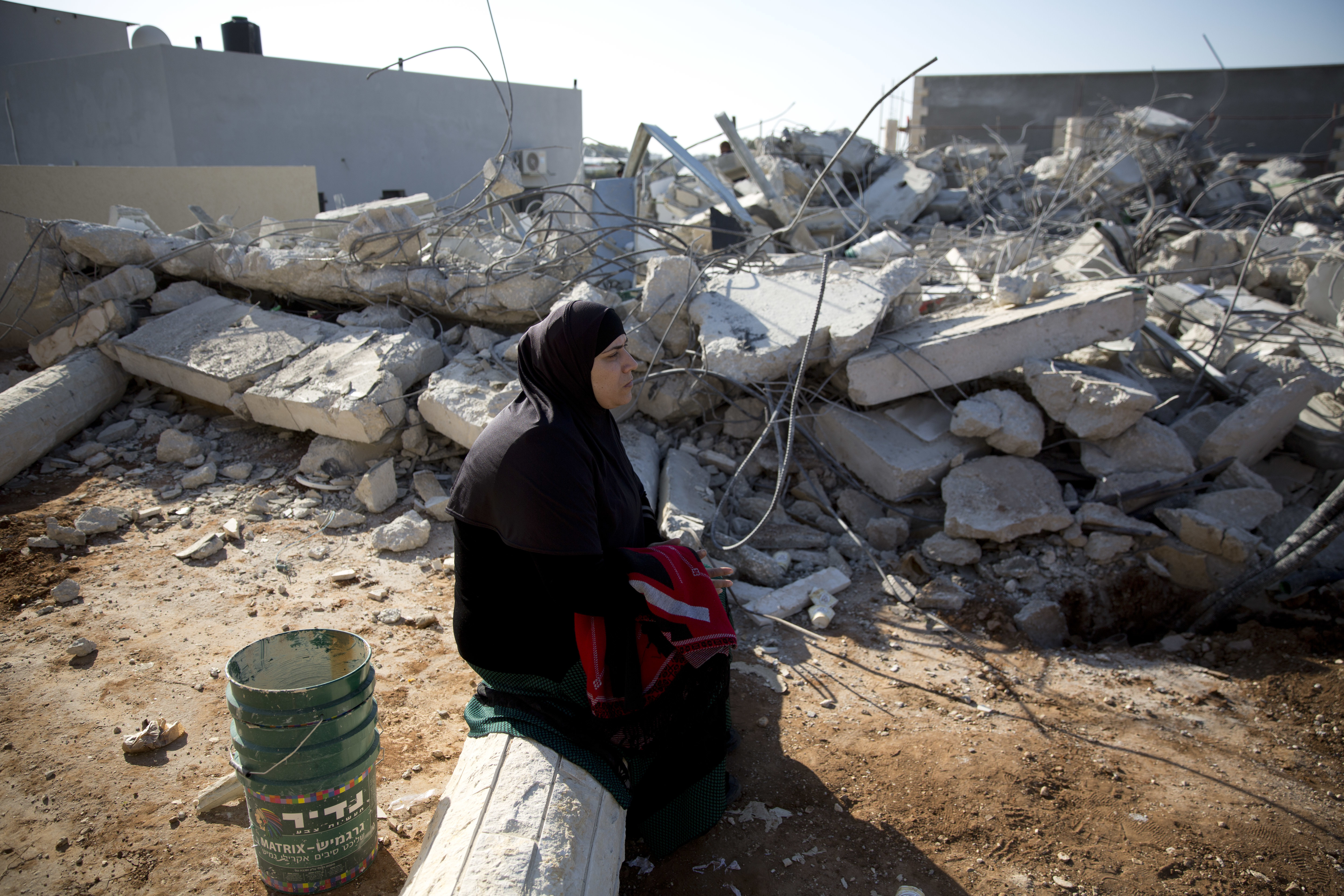 An Israeli Arab woman sits by the rubble of demolished house in Kalansua, Israel. Photo / AP