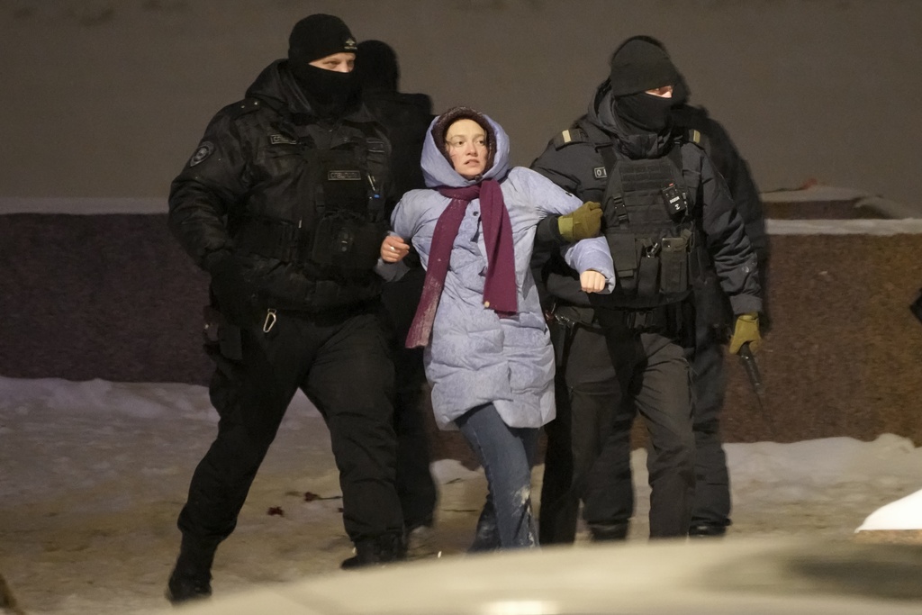 Police officers detain a woman who laid flowers for Alexei Navalny at the Memorial to Victims of Political Repression in St. Petersburg, Russia on February 16. (AP Photo)