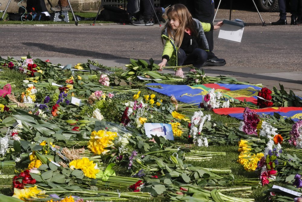 A child lays flowers outside the Cambridge gate of Windsor Castle in Windsor. Photo / AP