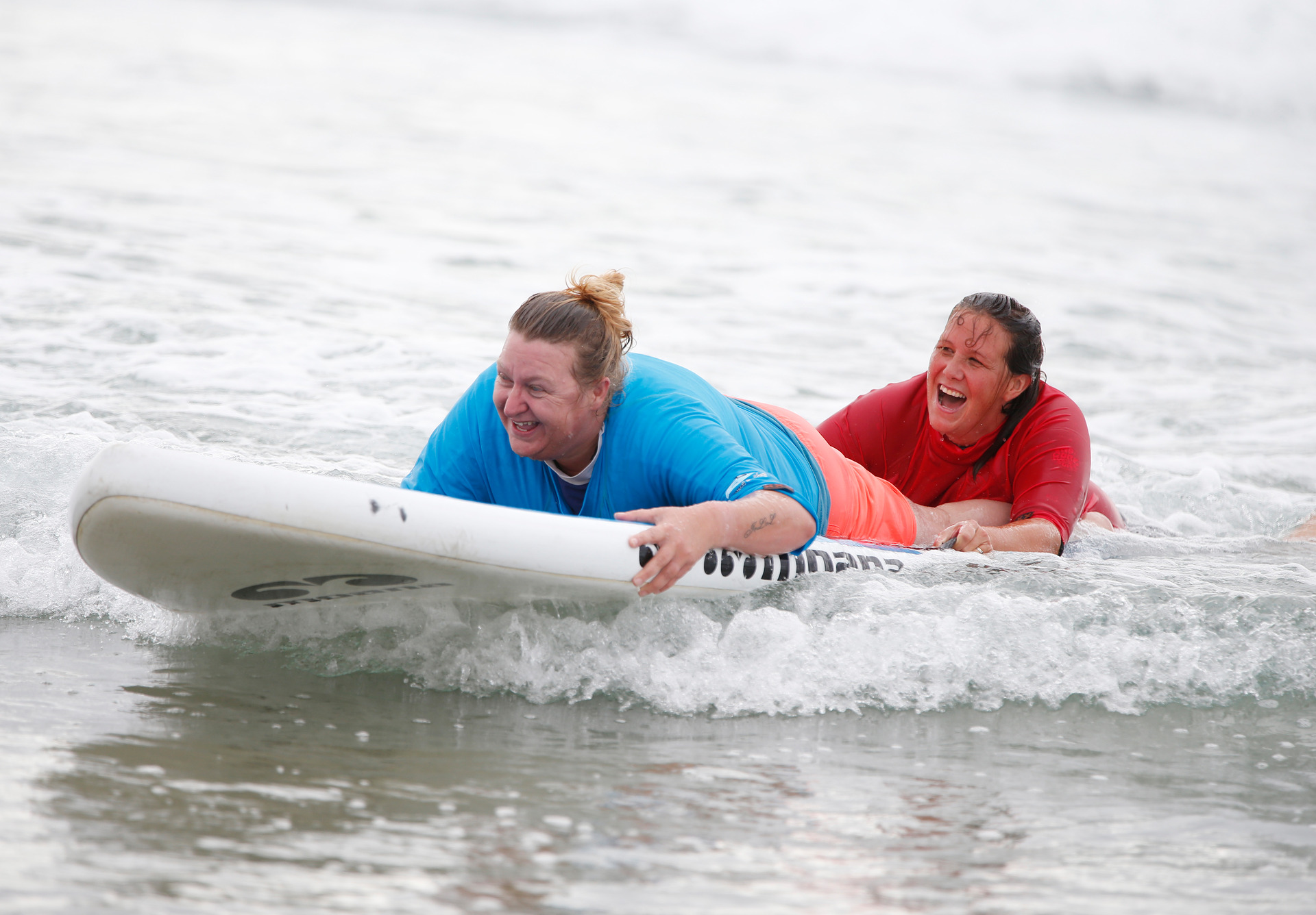 Melissa Mallaby from Whangārei and volunteer and surf instructor Kelly Comery enjoy the surf. 