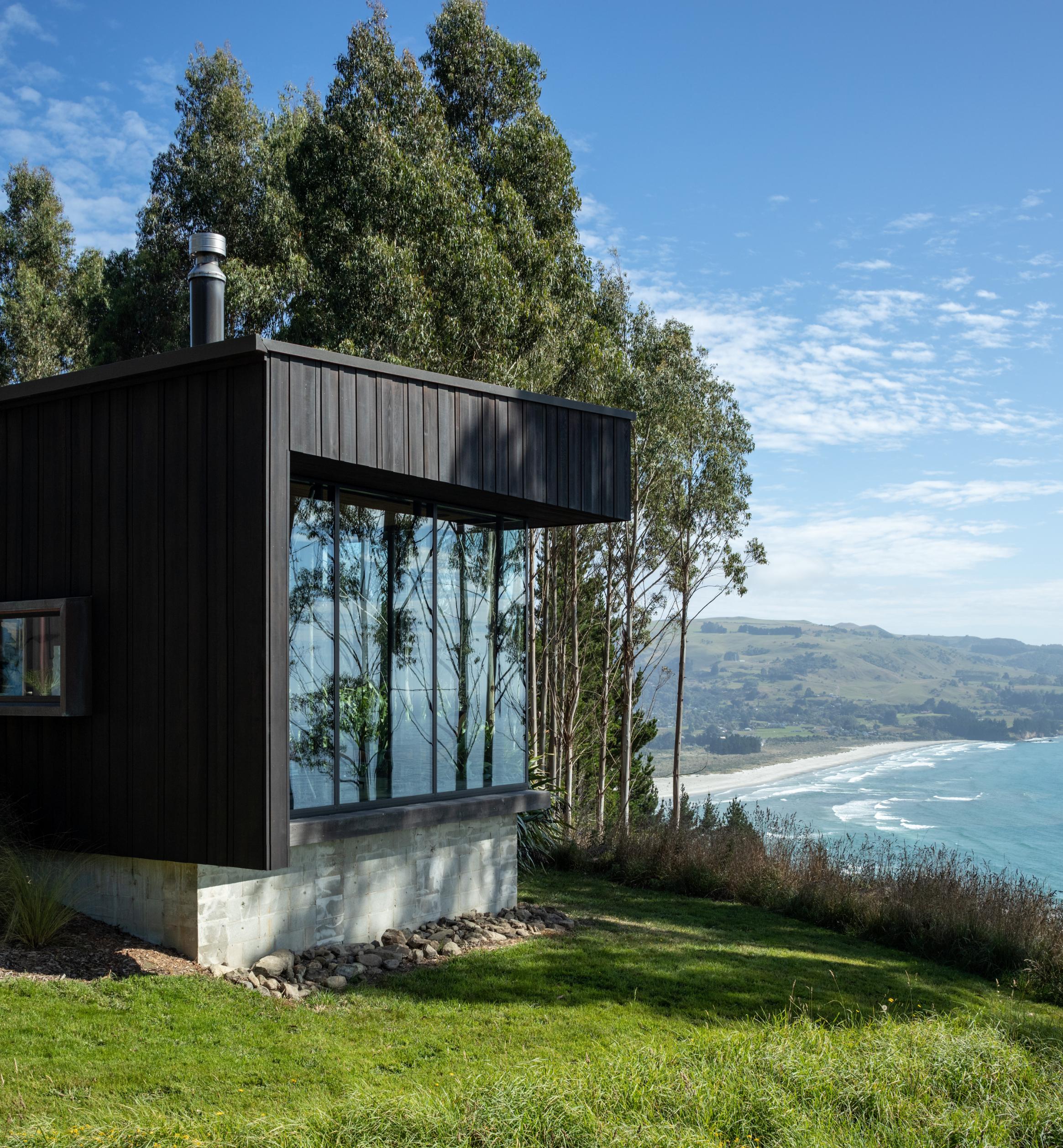 Black-stained cedar cladding lets the buildings disappear in their own shadow. Photo / Simon Devitt