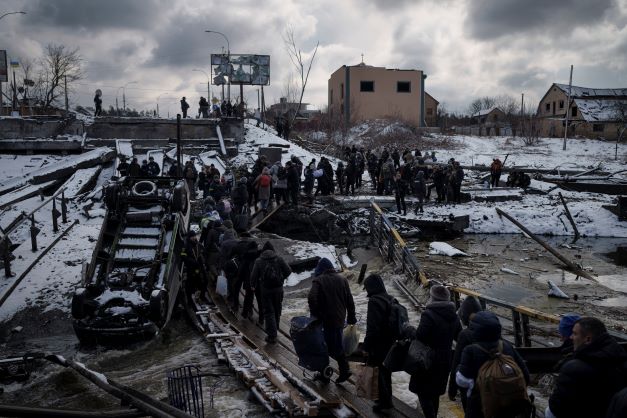 Ukrainians cross an improvised path under a destroyed bridge while fleeing Irpin, in the outskirts of Kyiv, Ukraine in March 2022. As milestones go, the first anniversary of Russia's invasion of Ukraine is both grim and vexing. It marks a full year of killing, destruction, loss and pain felt even beyond the borders of Russia and Ukraine. Photo / AP file 