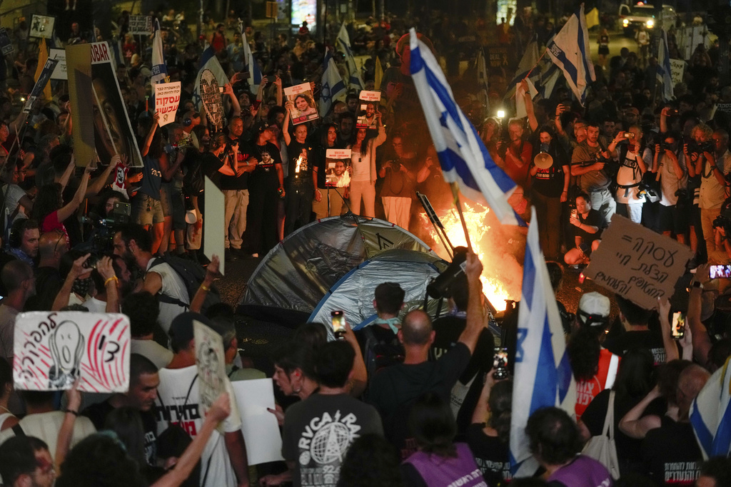 Demonstrators hold signs and pictures of hostages near a fire during a protest against Israeli Prime Minister Benjamin Netanyahu's government in Tel Aviv on June 15. Photo / AP
