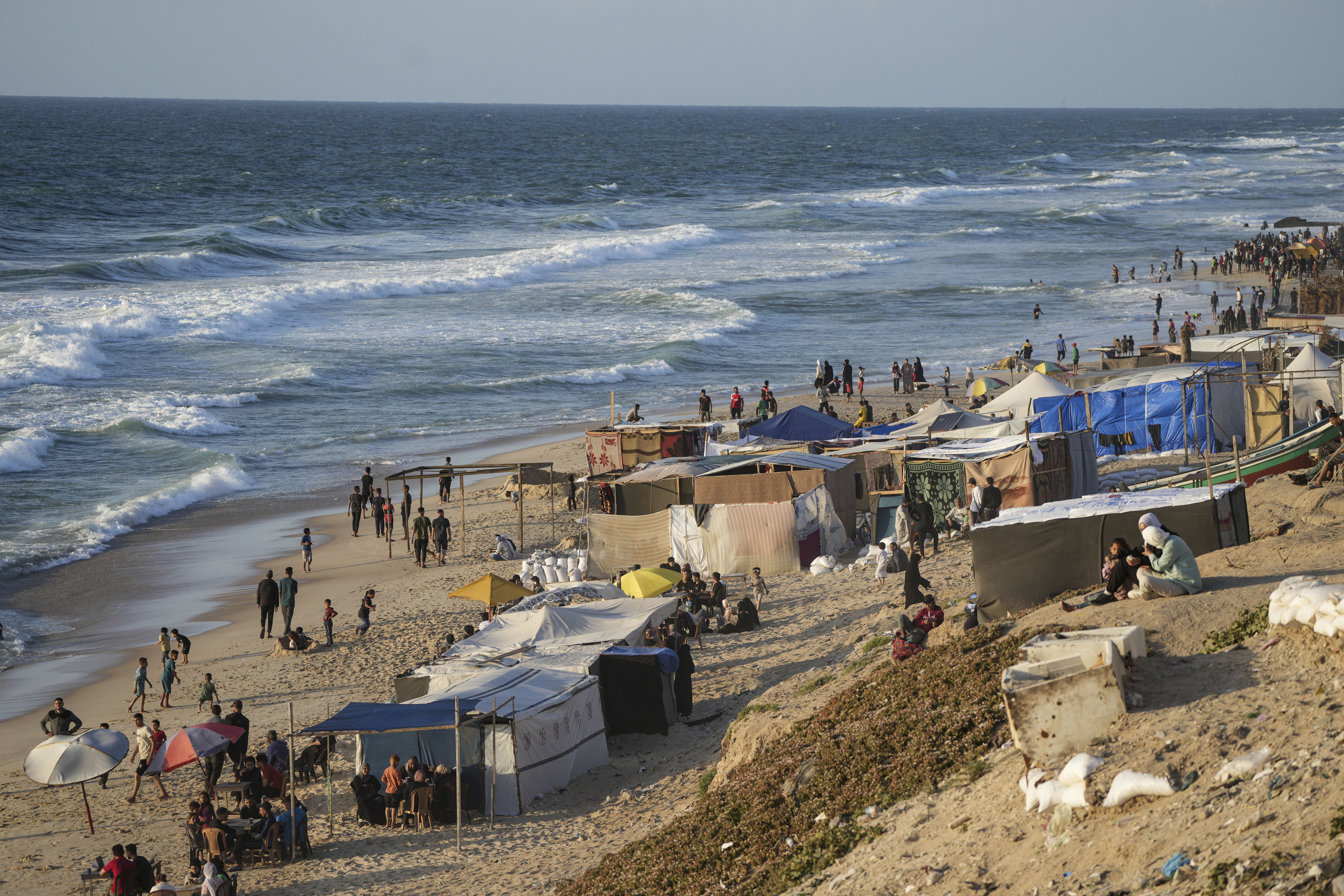 Palestinians displaced by the Israeli air and ground offensive on the Gaza Strip walk along a beach of Mediterranean Sea at a makeshift tent camp in Deir al Balah. Photo / AP
