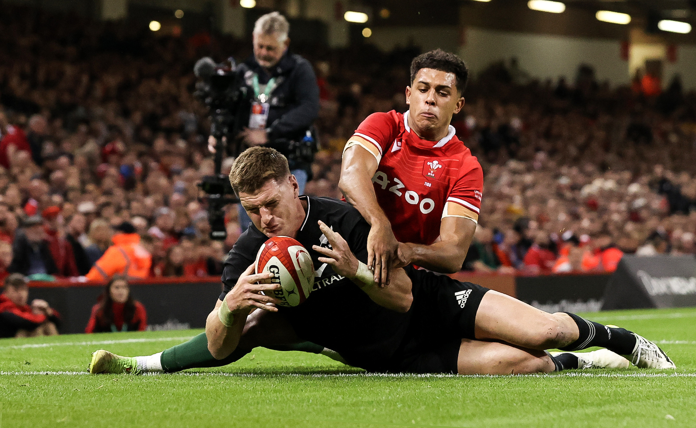 New Zealand’s Jordie Barrett scores a try despite the efforts of Wale’s Rico Dyer. Photosport