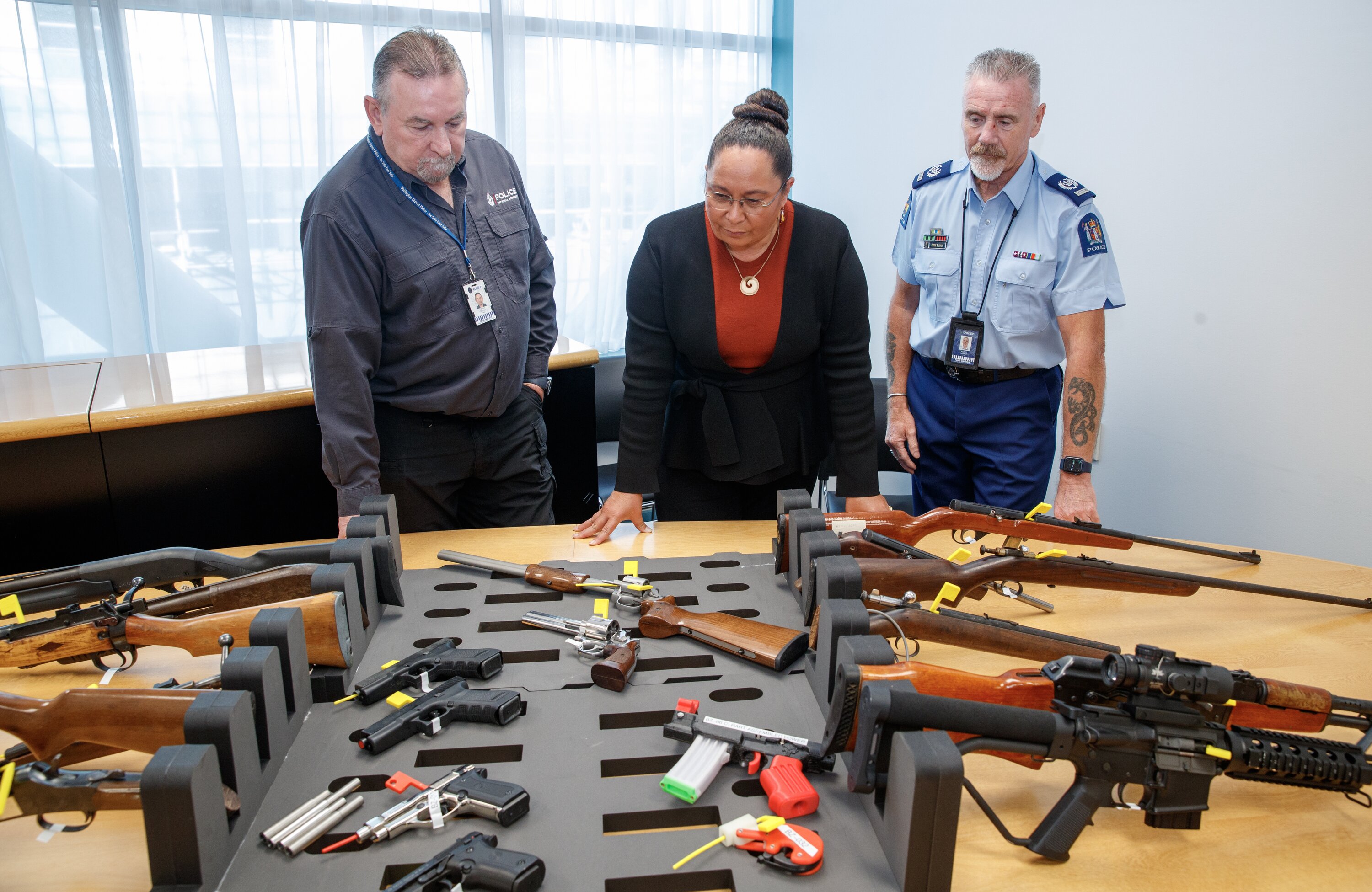 Associate Justice Minister Nicole McKee with Senior Armourer Terry Quirke, left, and Senior Sergeant Paddy Hannon, inspecting seized illegal firearms after announcing the Firearms Prohibition Orders bill. Photo / Mark Mitchell.
