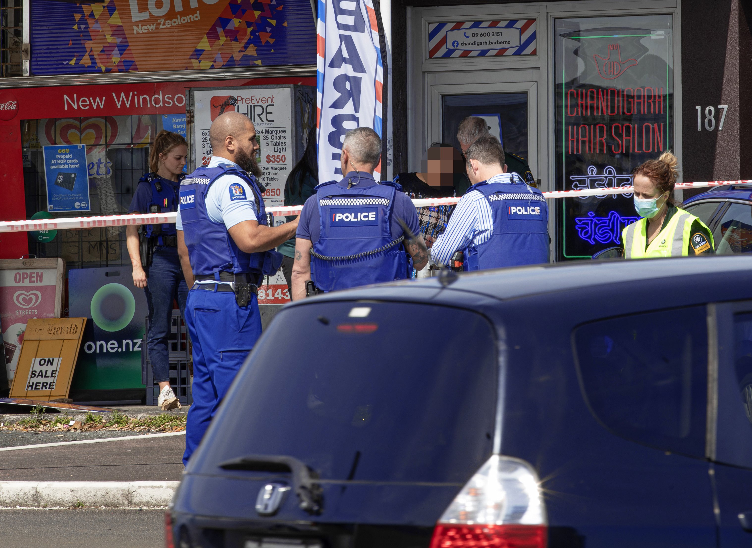 Police assist a woman after a stabbing at a New Windsor dairy in Auckland. Photo / Hayden Woodward