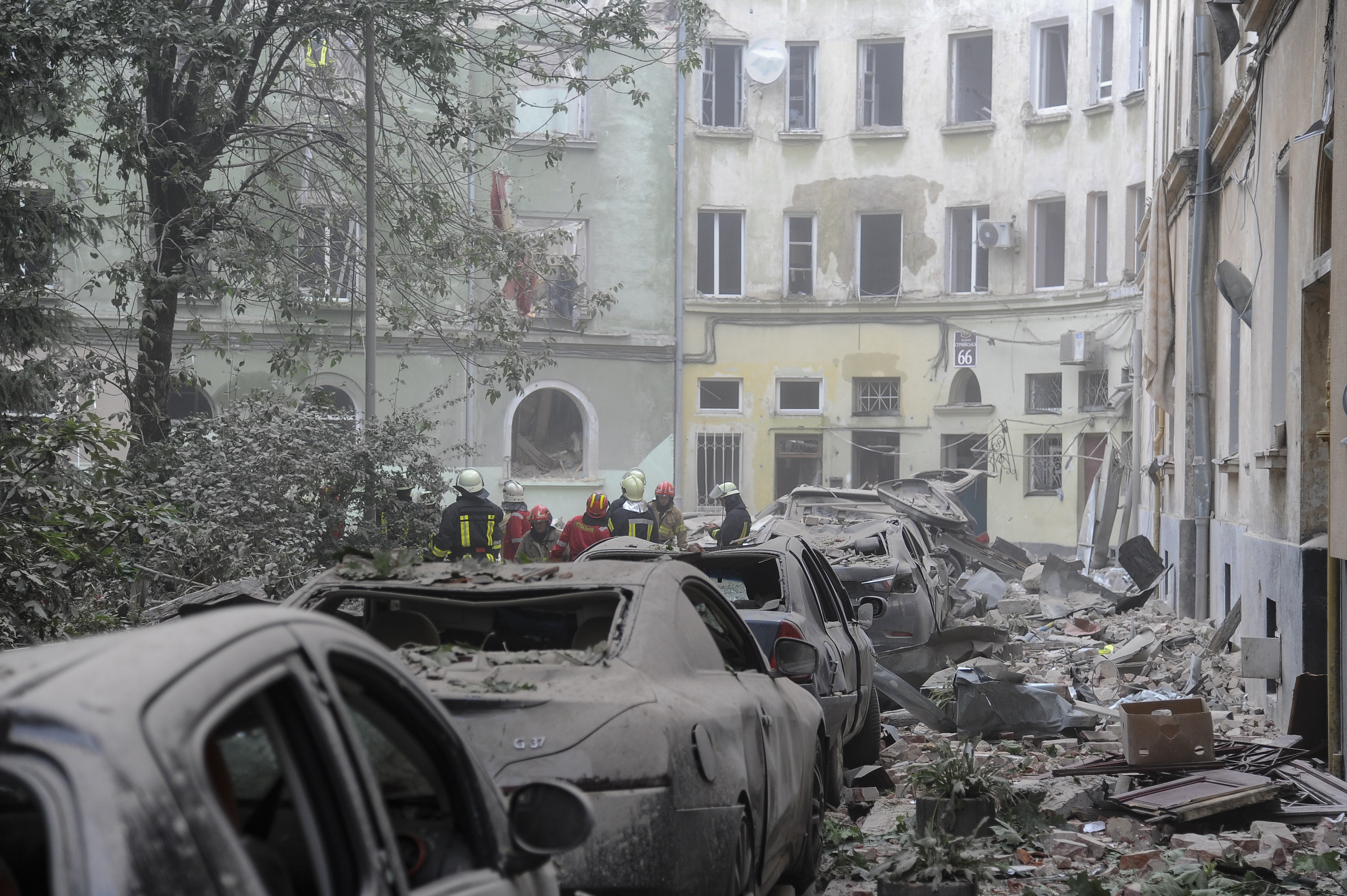 Emergency service workers gather outside damaged buildings as search for victims continues following a Russian missile attack in Lviv, Ukraine. Photo / AP