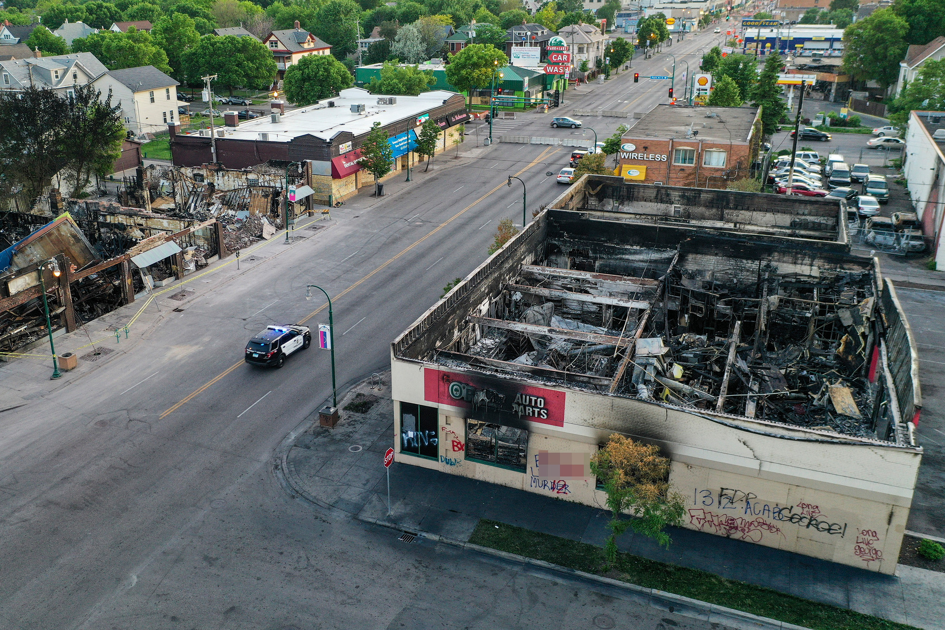 A police vehicle passes a building on East Lake Street that was destroyed during protests 
 in Minneapolis. Photo / AP