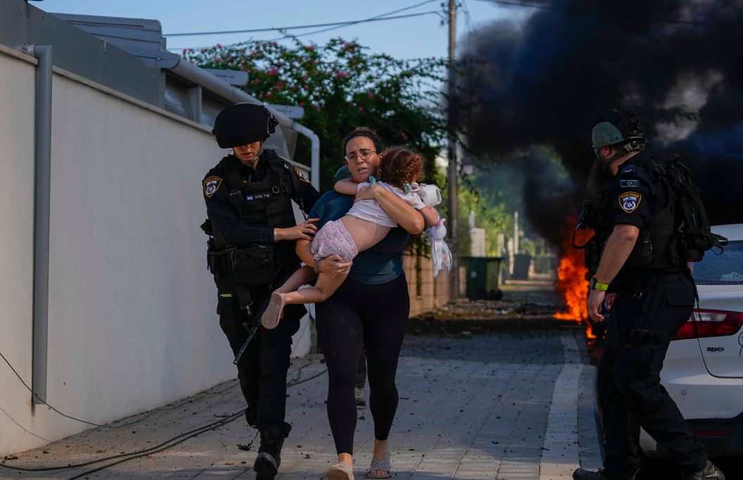 Israeli police evacuate a woman and a child from a site hit by a rocket fired from Gaza. Photo / AP