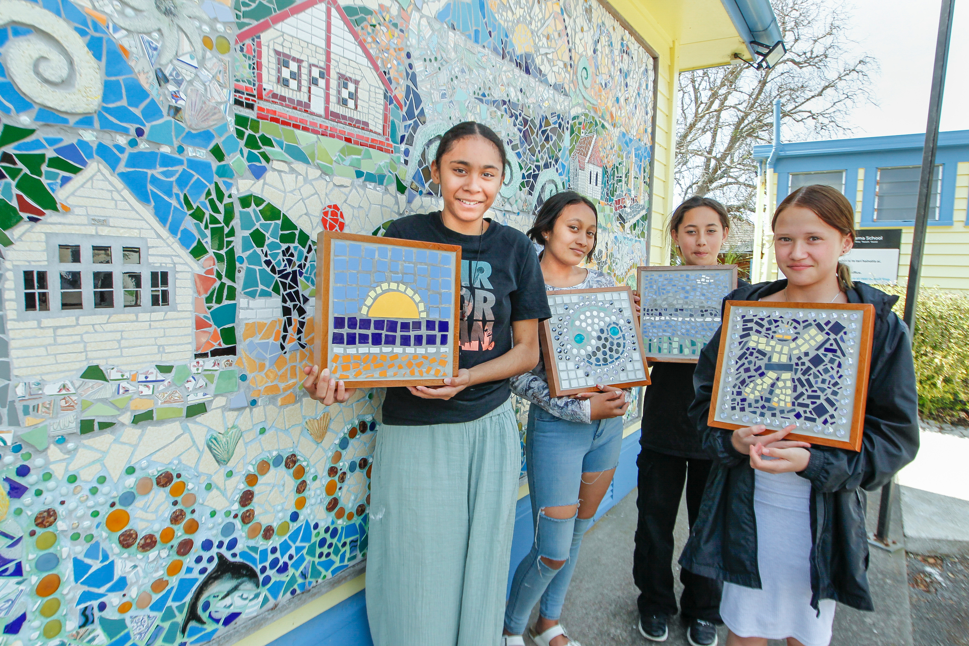 Merena Tahat-Timas (left), Anika Tapiata-Harmer, Horiana Tahau and Georgia Epere with their mosaics in front of a mosaic commemorating 100 years of Waim​ārama School, funded through Creative in Schools. Photo / Warren Buckland