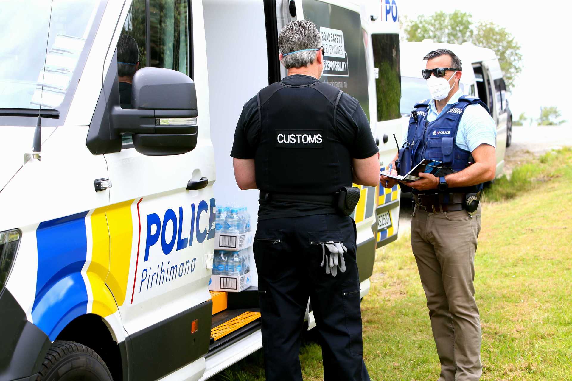 Detective Senior Sergeant Kevan Verry, of the Organised Crime Unit, speaks to a Customs officer outside an address on Takahiwai Rd in One Tree Point. Photo / Tania Whyte