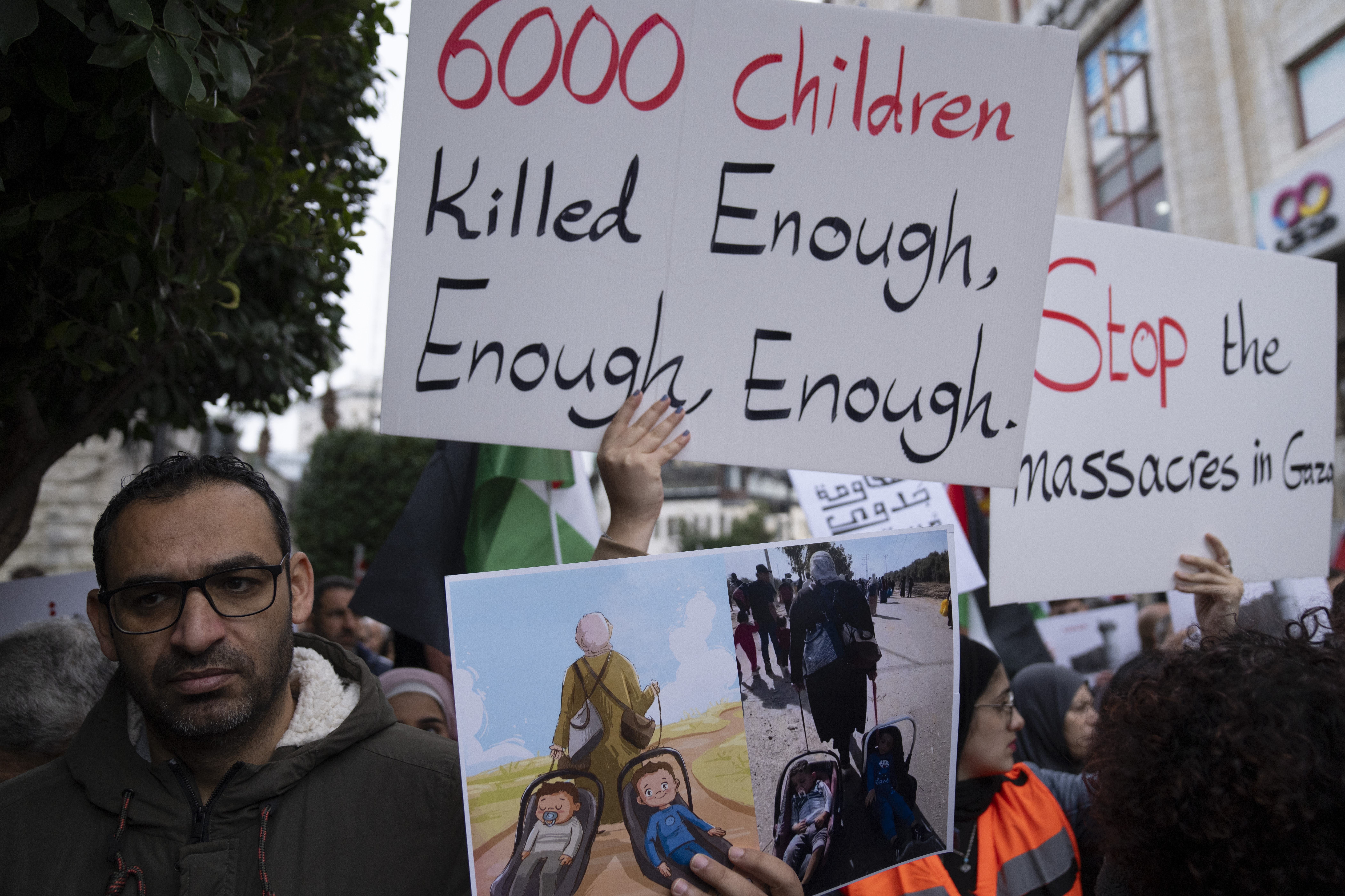 Palestinian protesters carry posters and chant anti-Israel slogans during a rally in solidarity with Gaza, in the West Bank city of Ramallah on November 22. (AP Photo/Nasser Nasser)