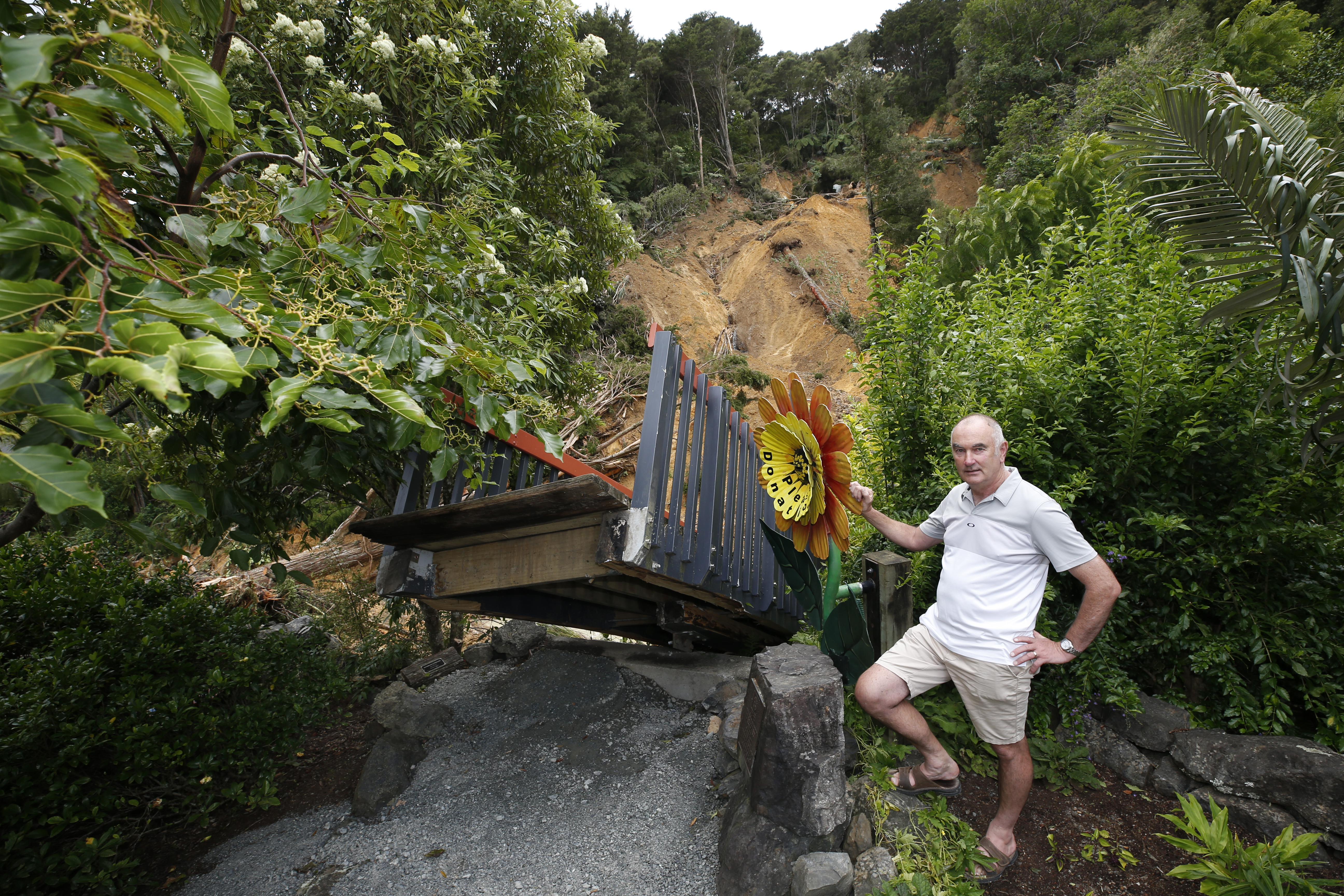 Guy Hessell pictured here with a slip that destroyed a bridge in the gardens. Photo / Michael Cunningham