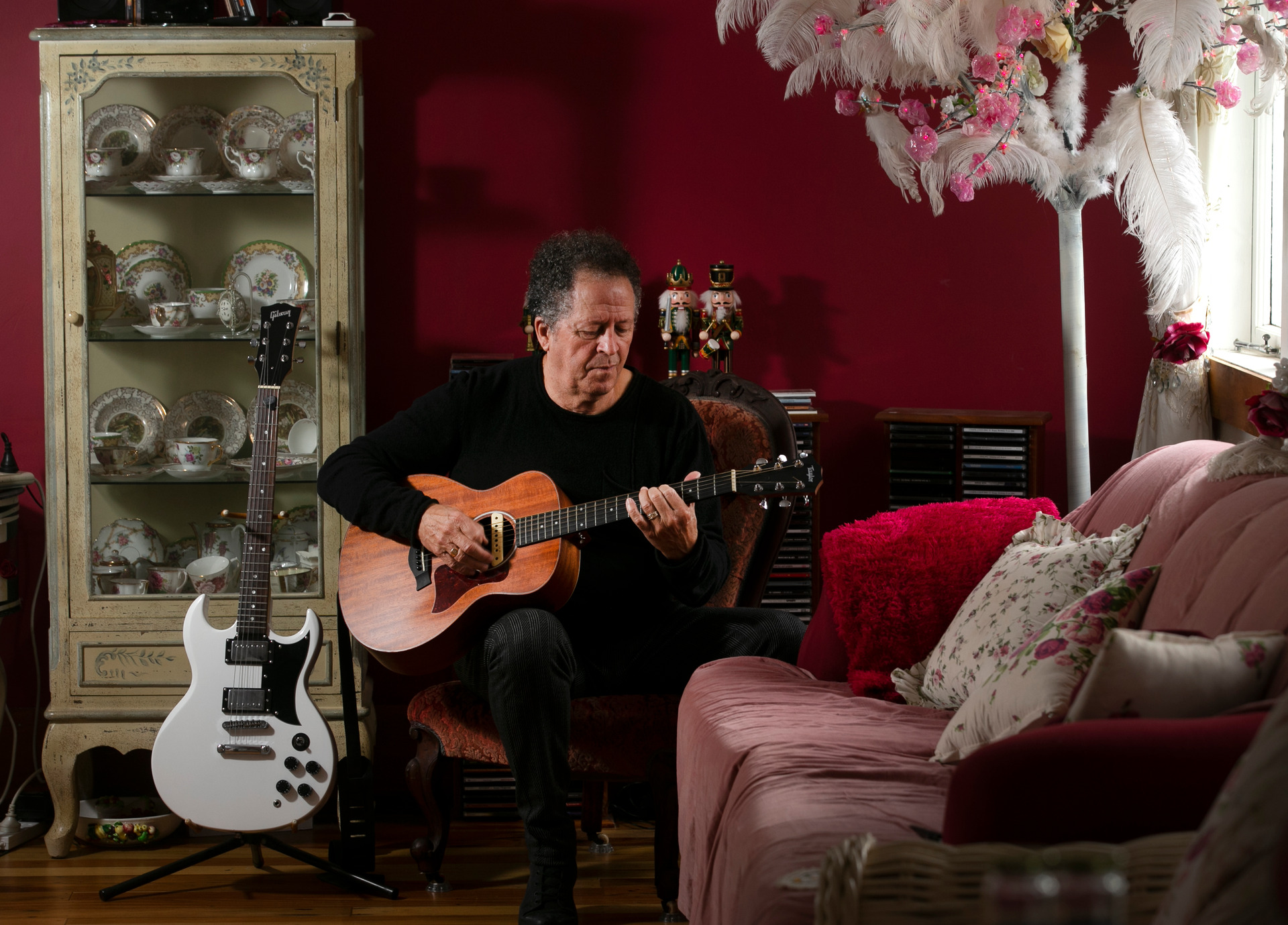 Musician Evan Silva pictured playing guitar in the beautifully eclectic living room of his home in Paeroa today. Photo / Alan Gibson.