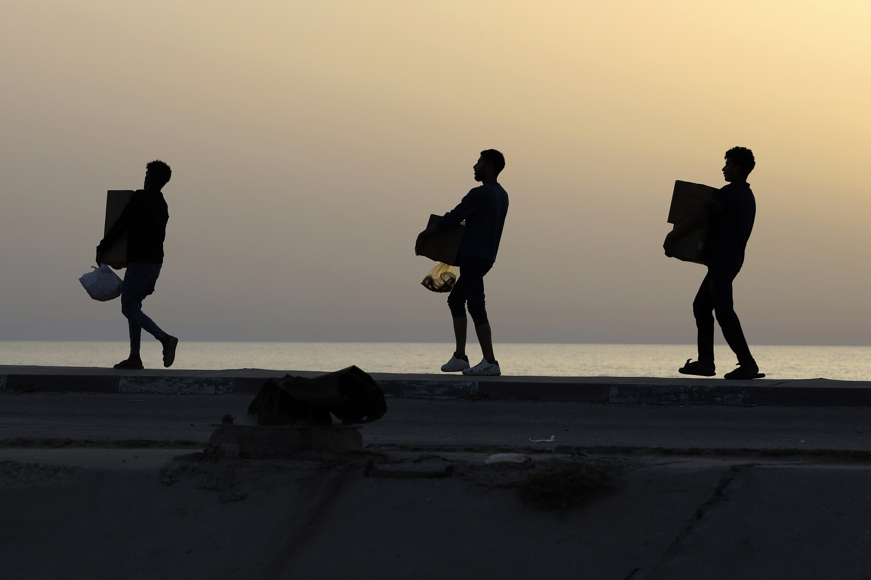 Palestinians carry aid boxes after storming trucks loaded with humanitarian aid brought in through a new US-built pier. Photo / AP