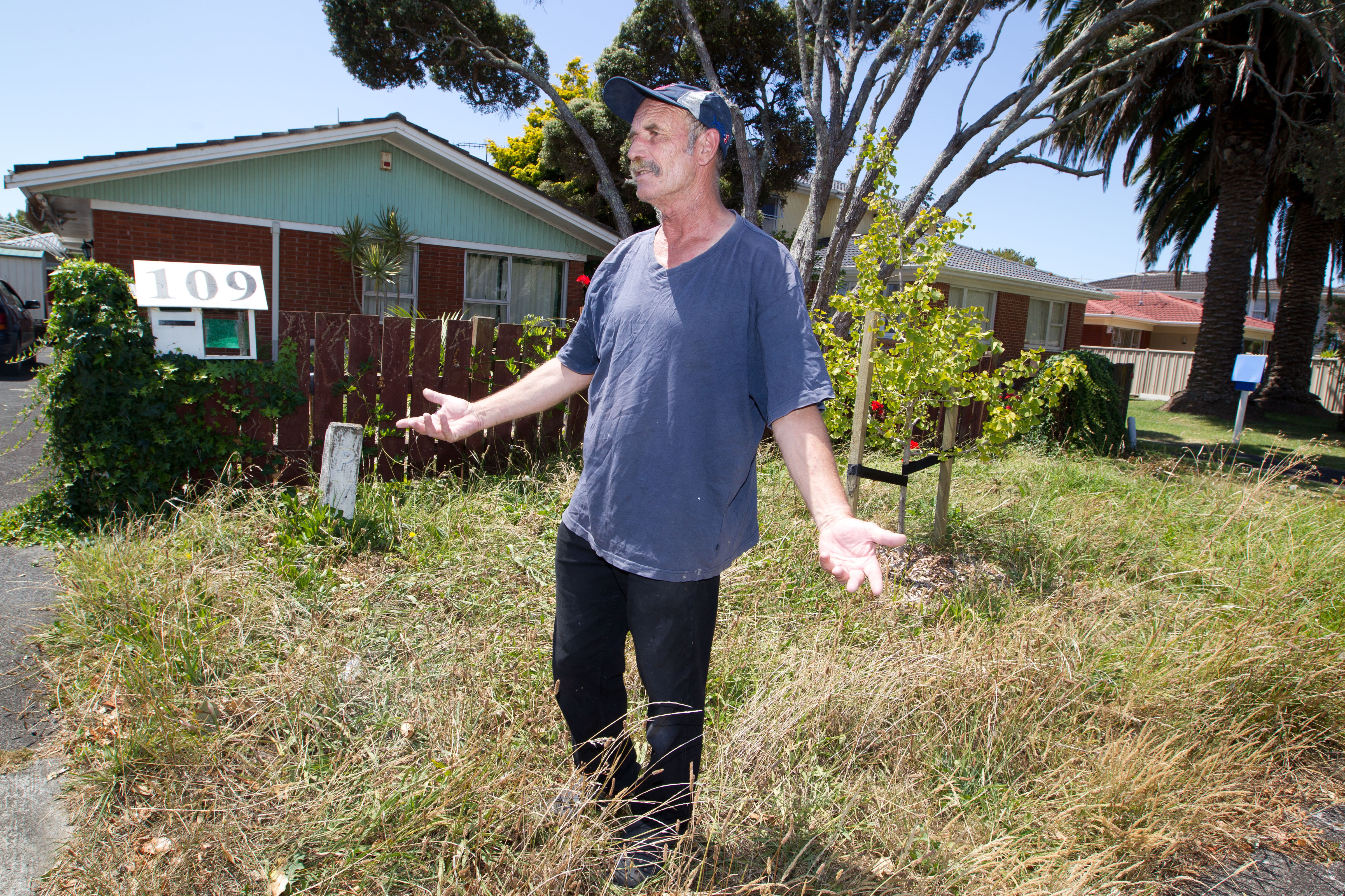Chris Mills with an overgrown grass berm outside his property on Celtic Crescent, Ellerslie in 2014.