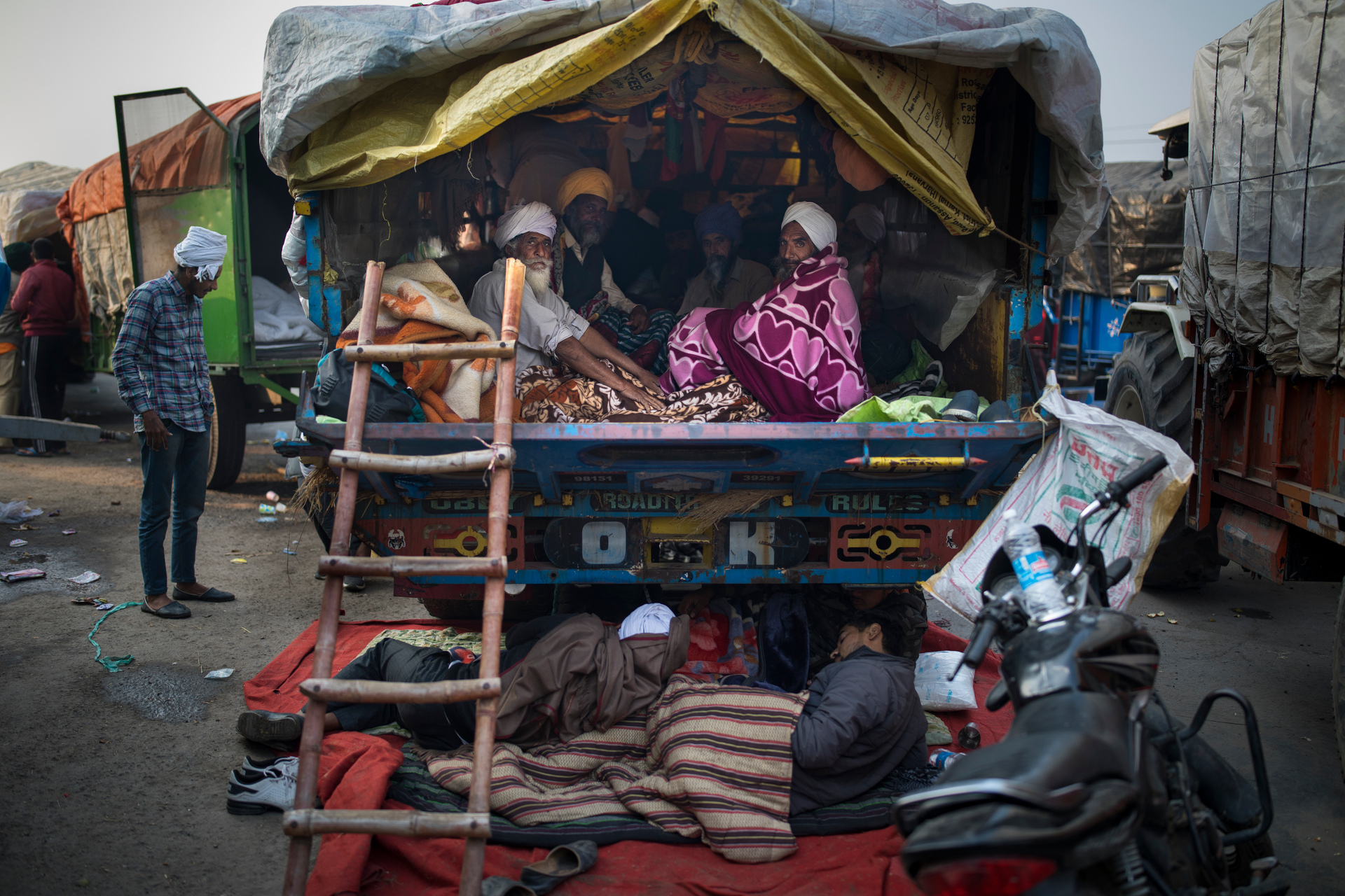 Indian farmers huddle together in the back of their tractor trailer early morning, sleeping in cold and wet conditions. Photo / AP