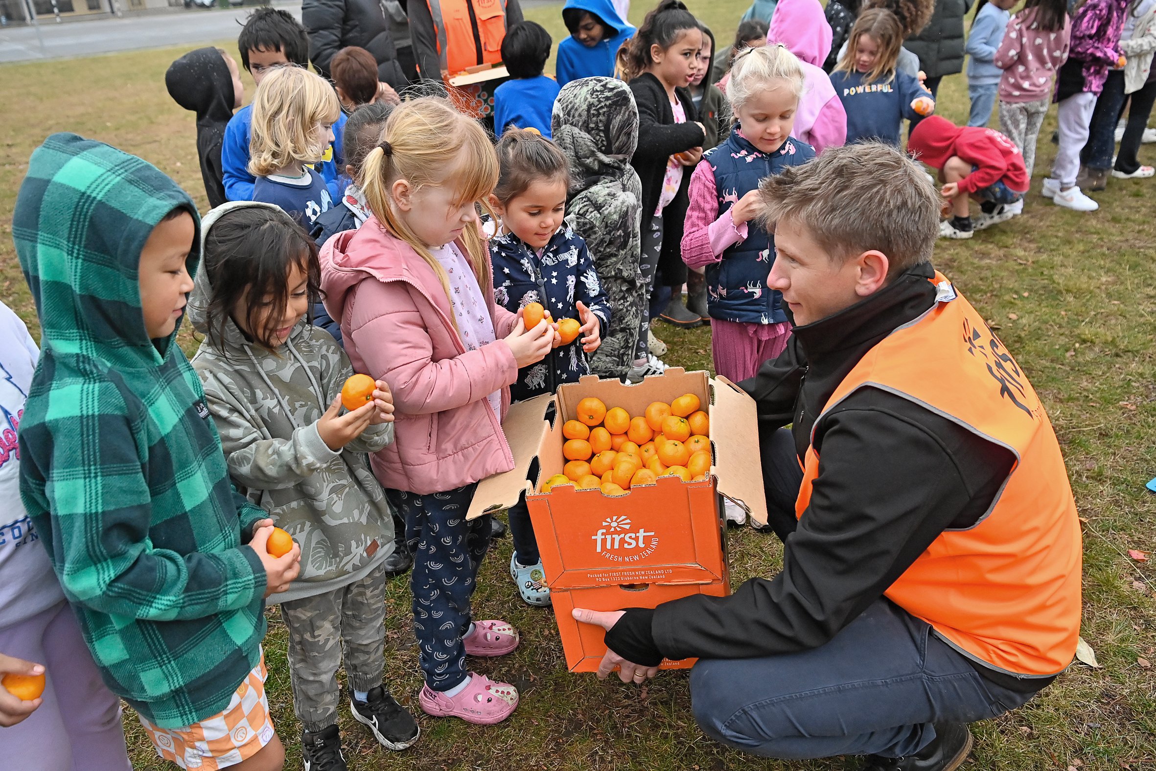 Simon Wilson of First Fresh hands out juicy mandarins to kids at Mangapapa School during Black Fern Renee Holmes' visit yesterday.
Photo /Paul Rickard