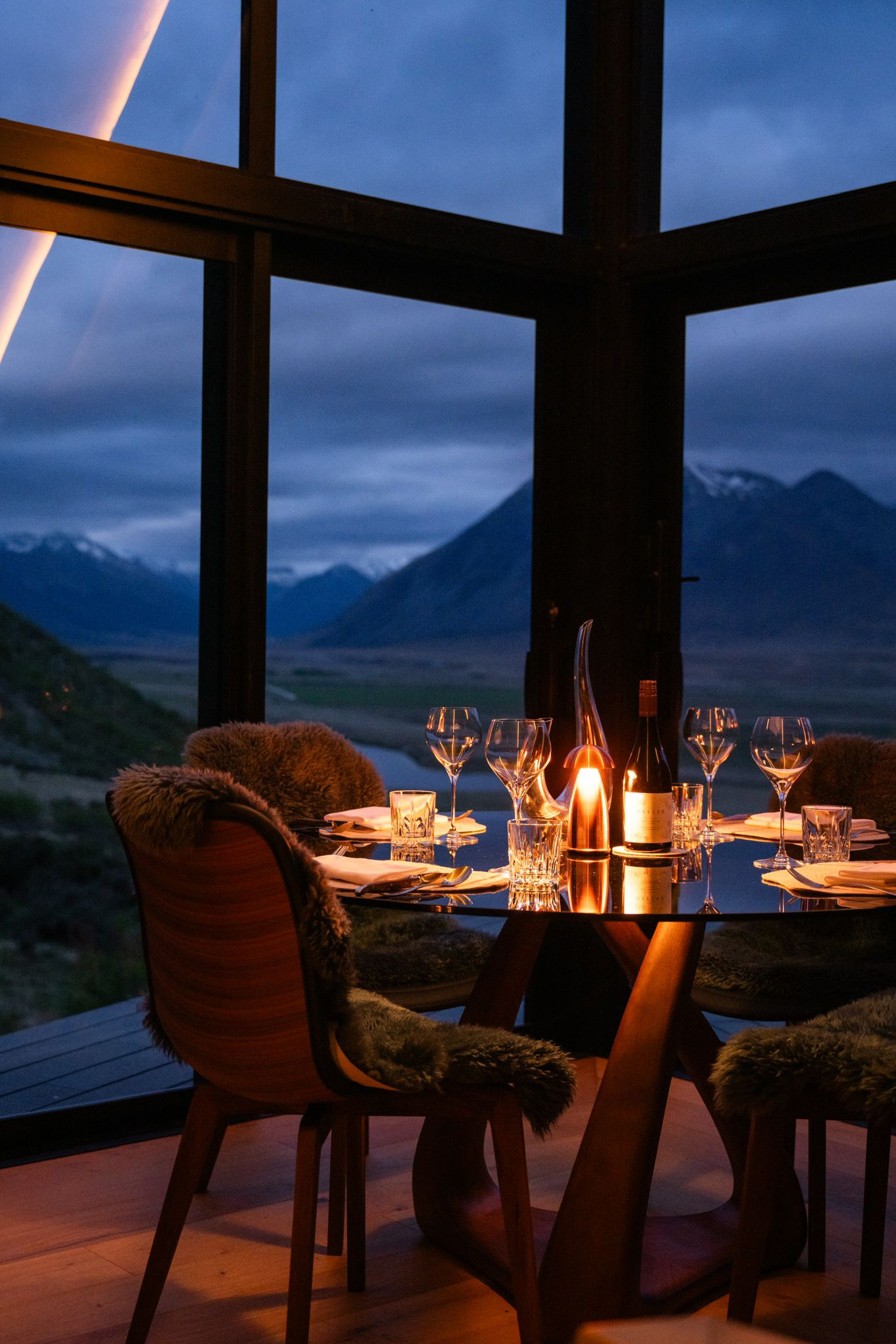 The interior of The Black Diamond at The Lindis includes valley views, padded dining for up to six people, and a pot-belly gas fireplace.
