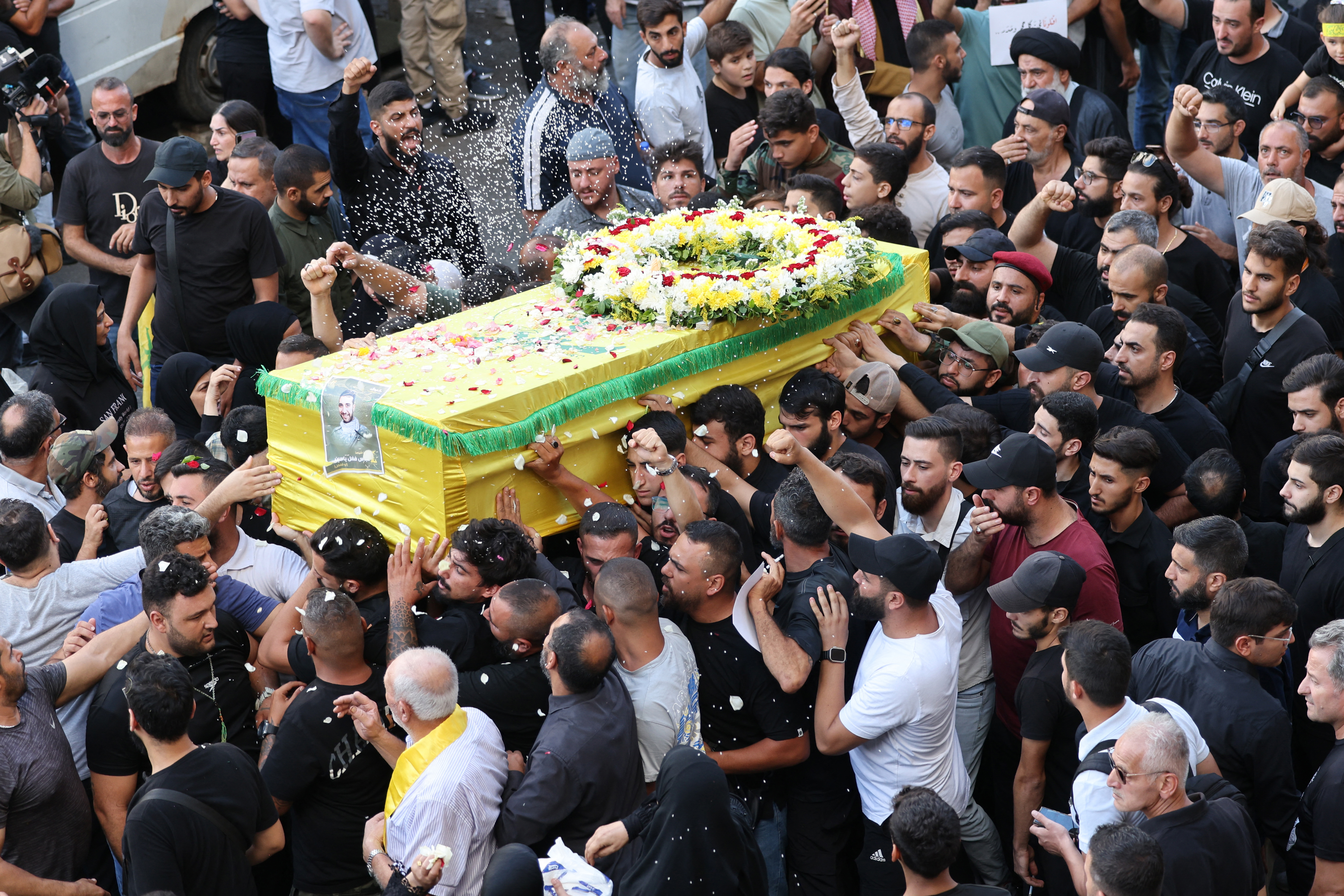 Mourners toss rice over the coffin of person a killed after hundreds of paging devices exploded in a deadly wave across Lebanon the previous day, during a funeral procession in Beirut's southern suburbs. Photo / AFP
