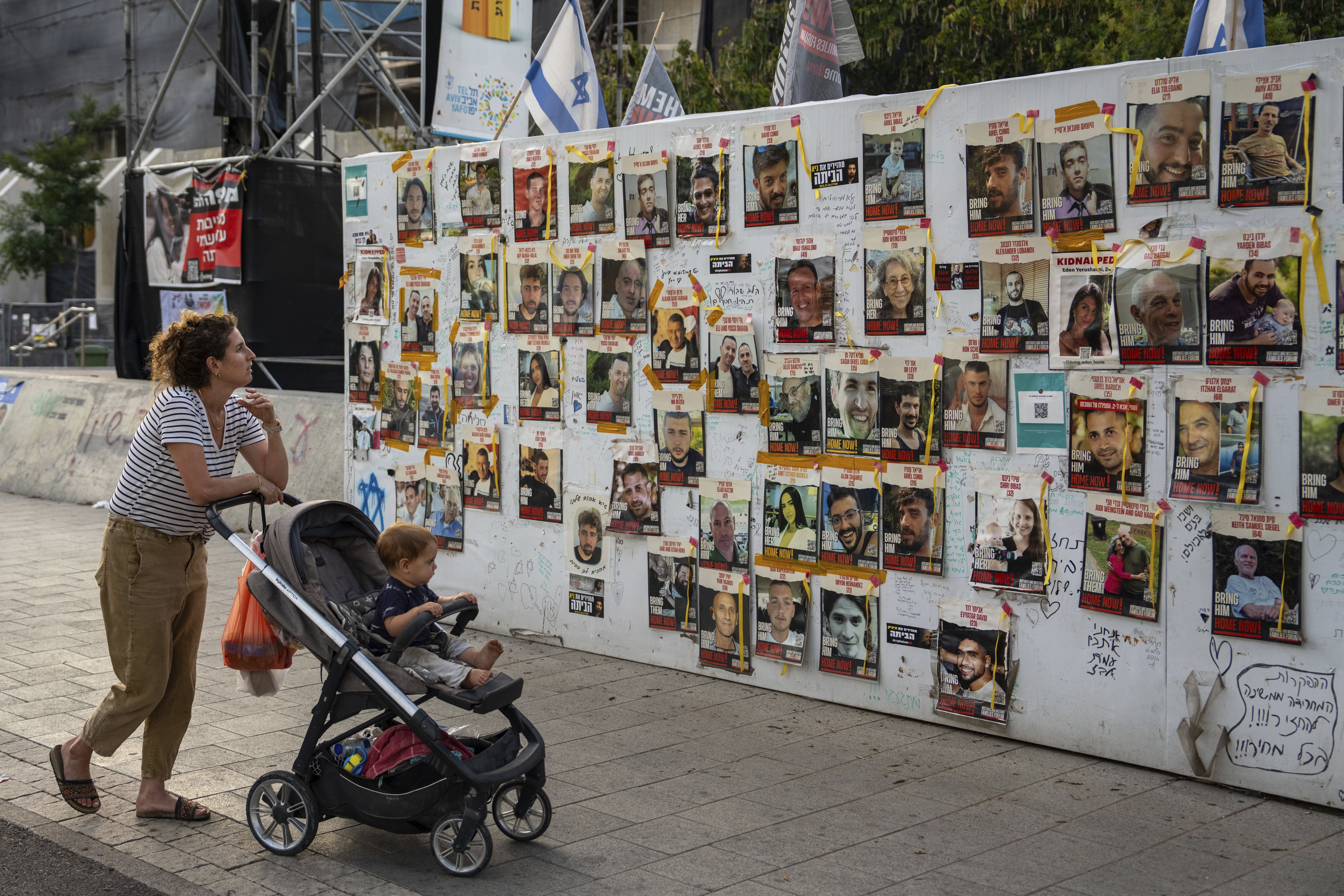 Passersby observe the photos of hostages held in the Gaza Strip that are plastered to the walls of a plaza known as Hostages Square in Tel Aviv, Israel. Photo / AP