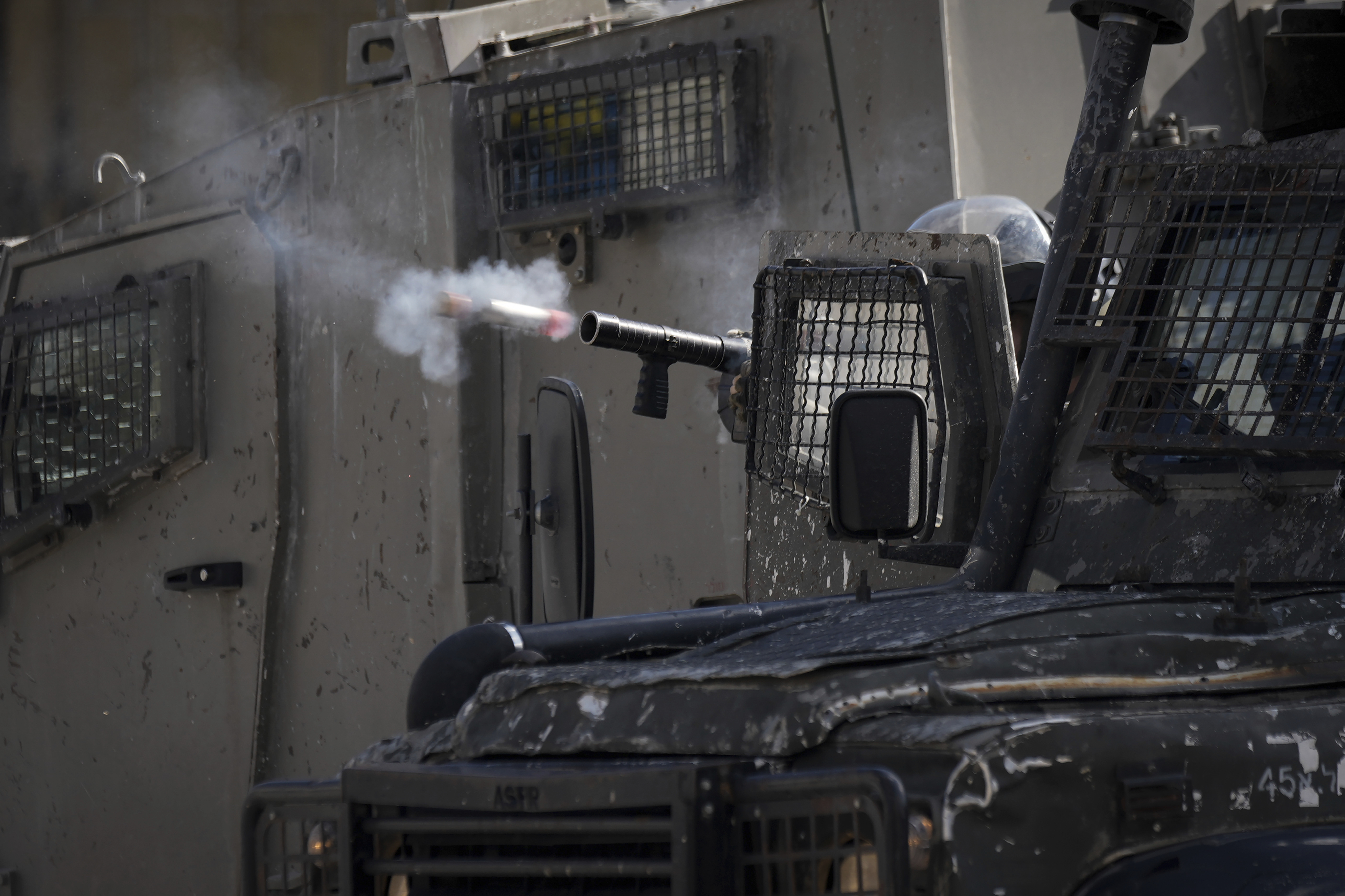 An Israeli officer fires tear gas at Palestinians during a military operation in the Balata refugee camp, West Bank. Photo / AP