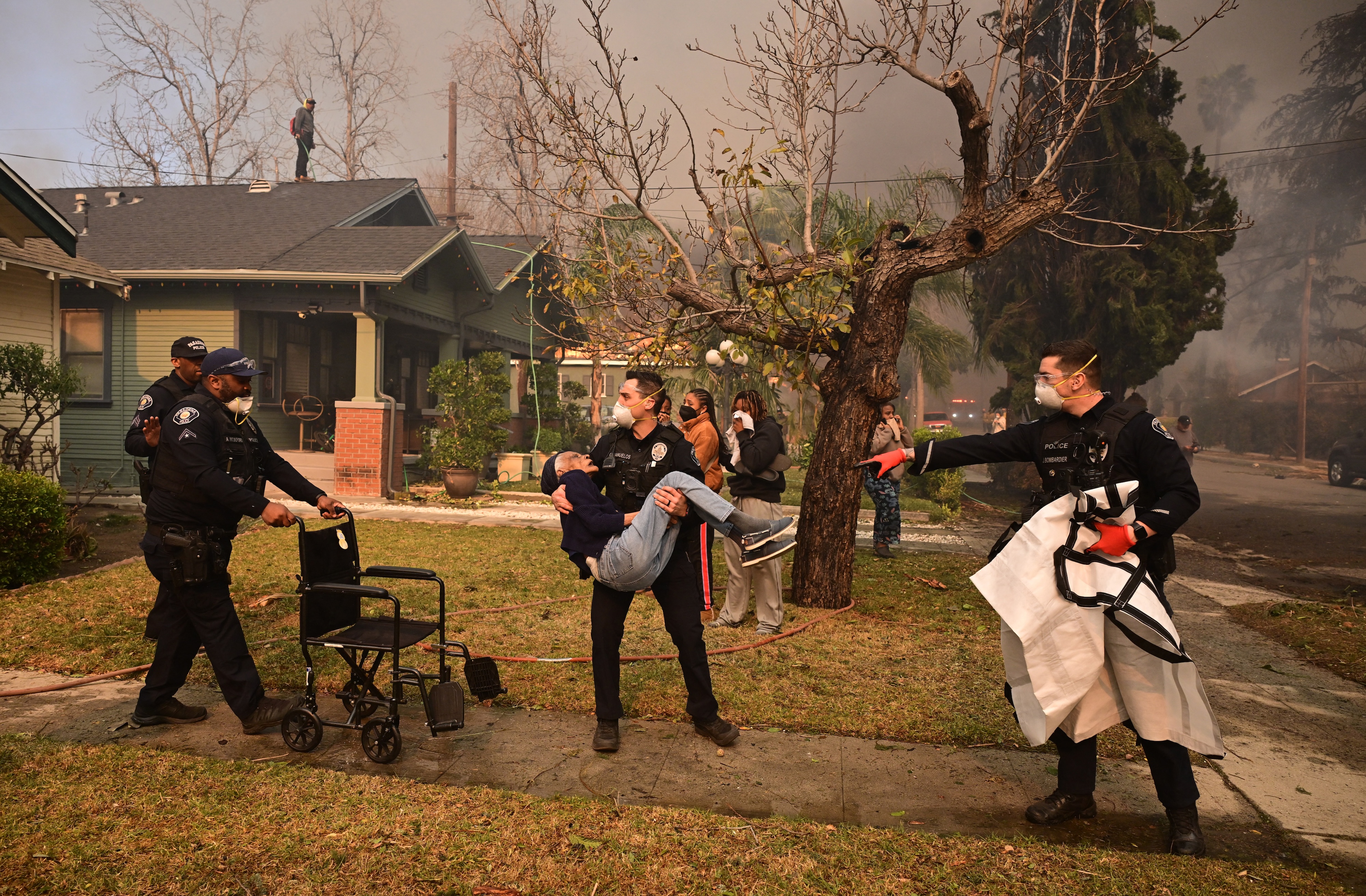 Police officers remove an elderly resident from her home during the Eaton fire in Altadena, California. Photo / AFP