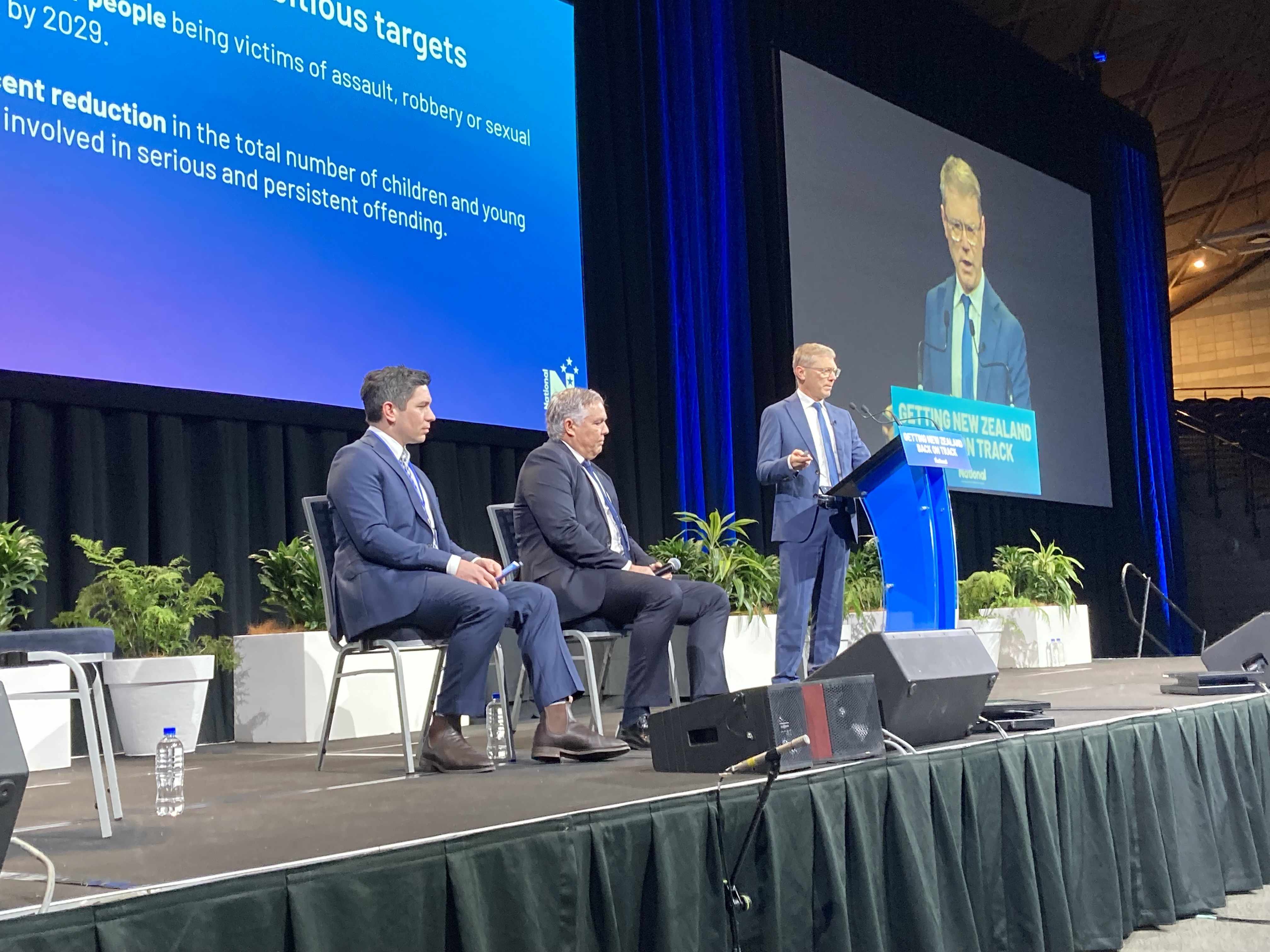 Justice Minister Paul Goldsmith speaks to the National Party conference with Police Minister Mark Mitchell and National MP James Meager (left) at the Manukau Due Drop Events Centre. Photo / Claire Trevett