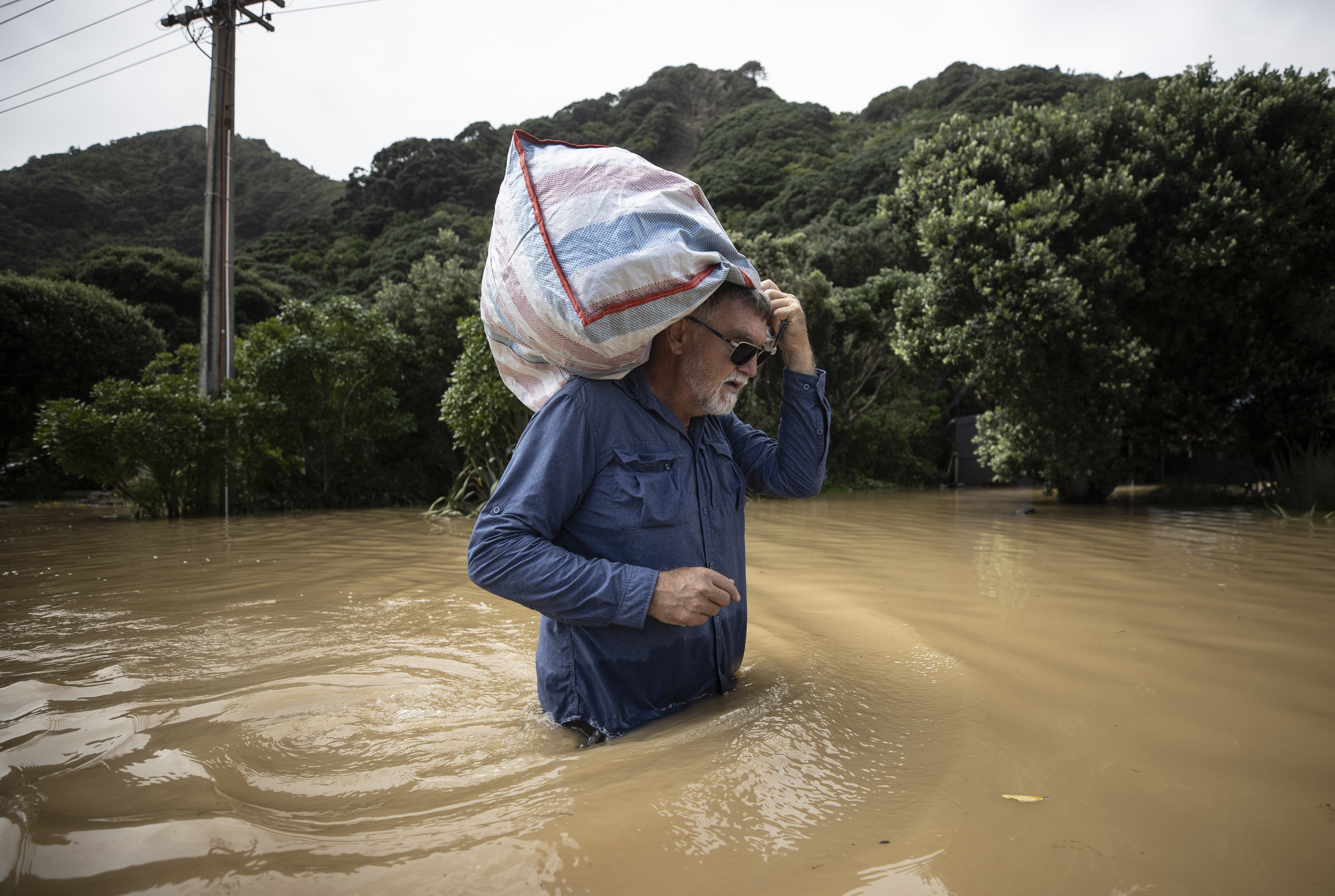 A Piha resident salvages personal belongings from his home after being cut off by Gabrielle's floodwaters. Photo / George Heard