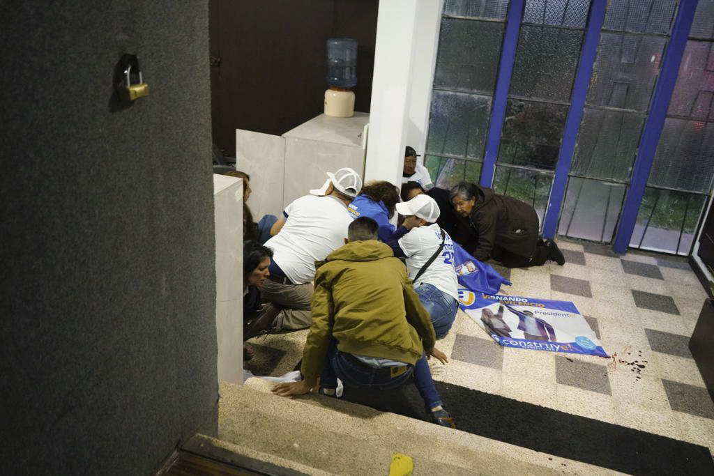 Supporters of presidential candidate Fernando Villavicencio take cover after he was shot and killed at the end of a campaign rally outside a school. Photo / AP