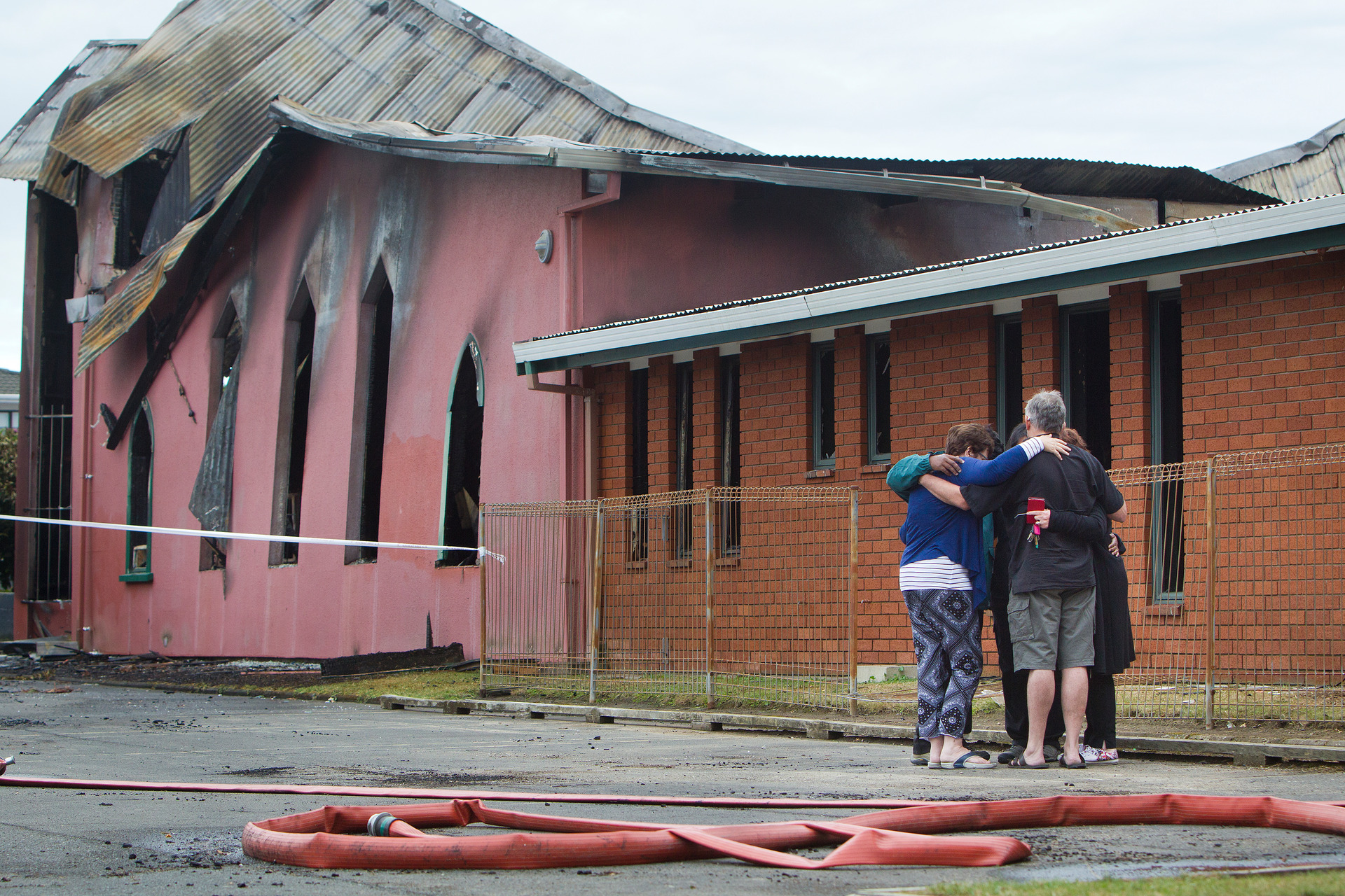People hug outside the devastated St John's Church. Photo / Stephen Parker
