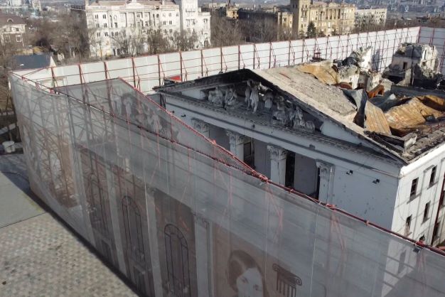 This December 2 image from video shows fencing surrounding the Drama Theatre in Mariupol, Ukraine. Months after hundreds died in Russian airstrikes on the theatre, the fencing is etched with Russian and Ukrainian literary figures as well as an outline of the theatre's previous life, before Russian occupation. Photo / AP