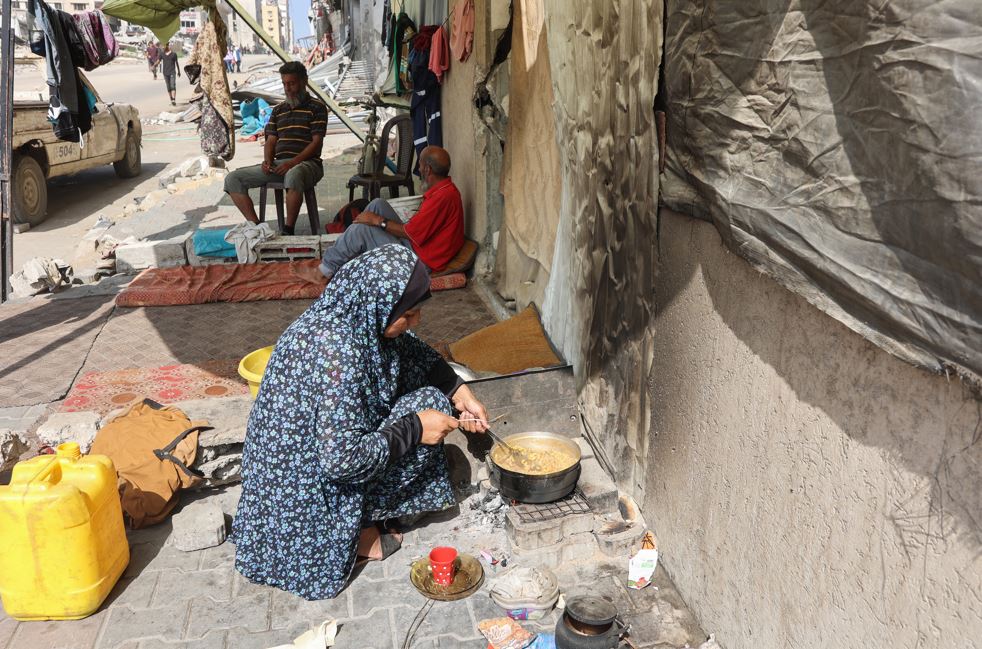 A woman cooks on an outdoor fire at a makeshift camp for Palestinians displaced from northern Gaza, at Gaza City's damaged Yarmouk stadium. Photo / AFP