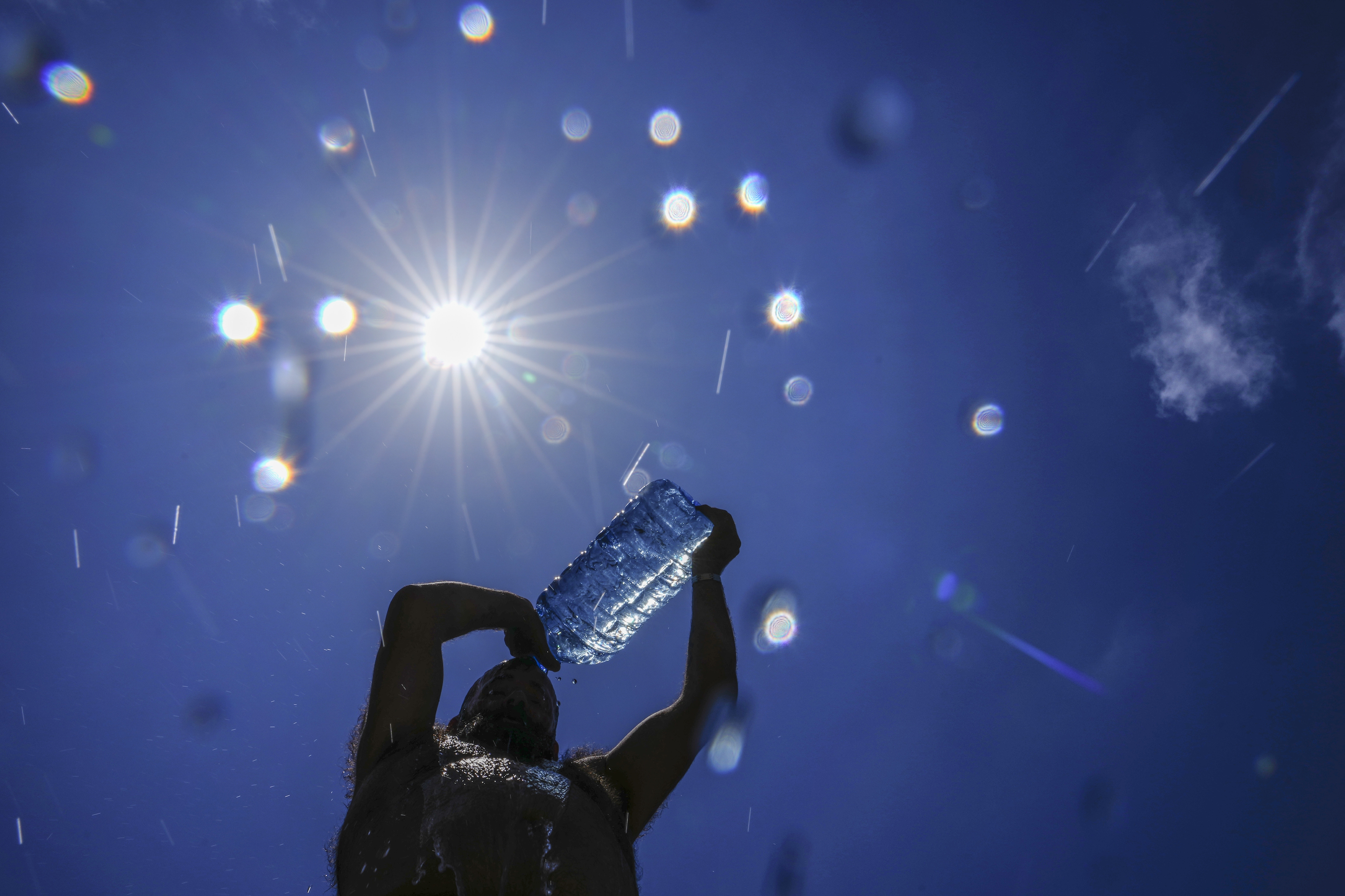 A man pours cold water on to his head to cool off on a sweltering hot day. Photo / AP