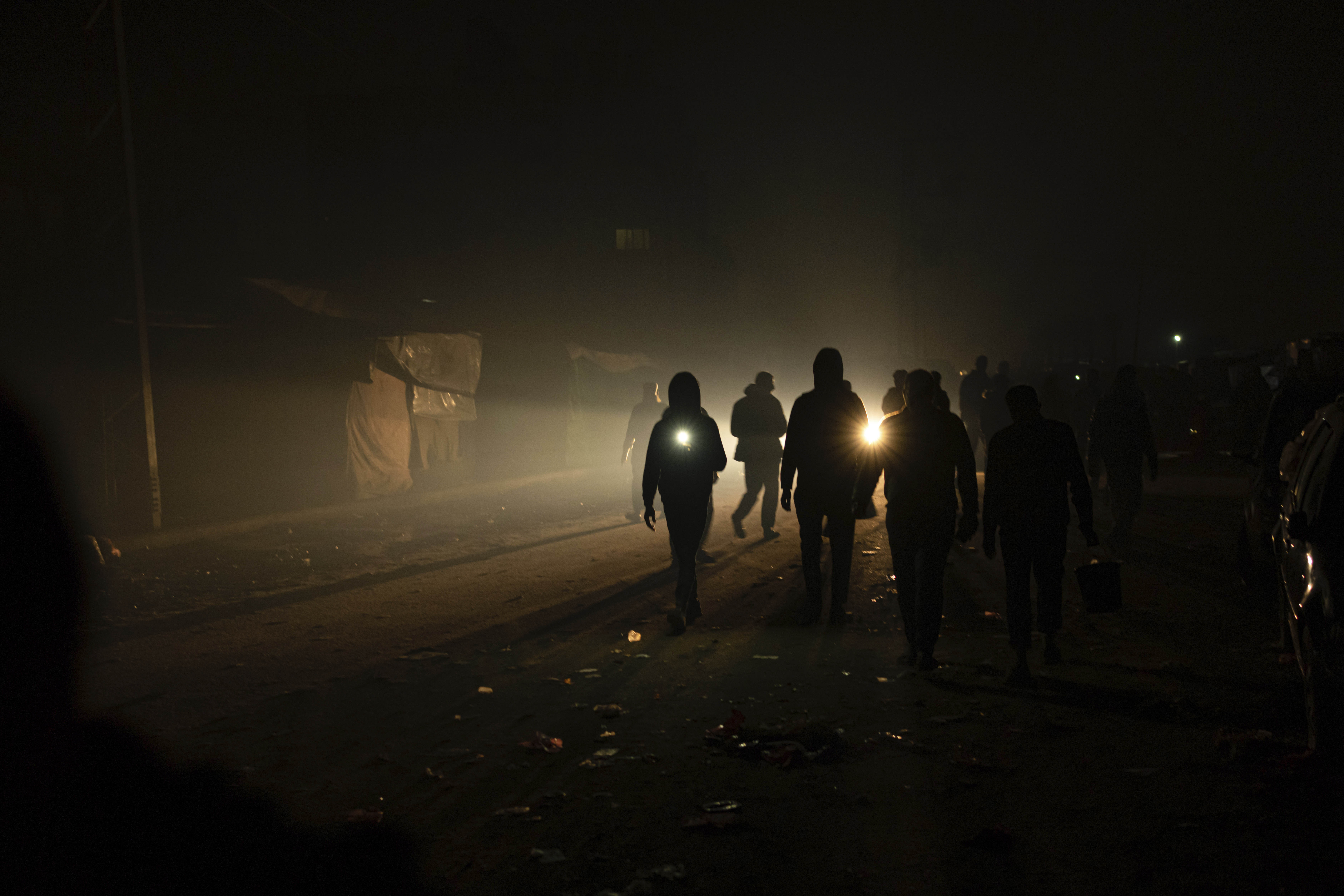 Palestinians displaced by the Israeli bombardment of the Gaza Strip walk in the dark with flashlights at the makeshift tent camp in the Muwasi area on Sunday, Israel has encouraged Palestinians to move to Muwasi, telling them they will be safe from bombing. Photo / AP
