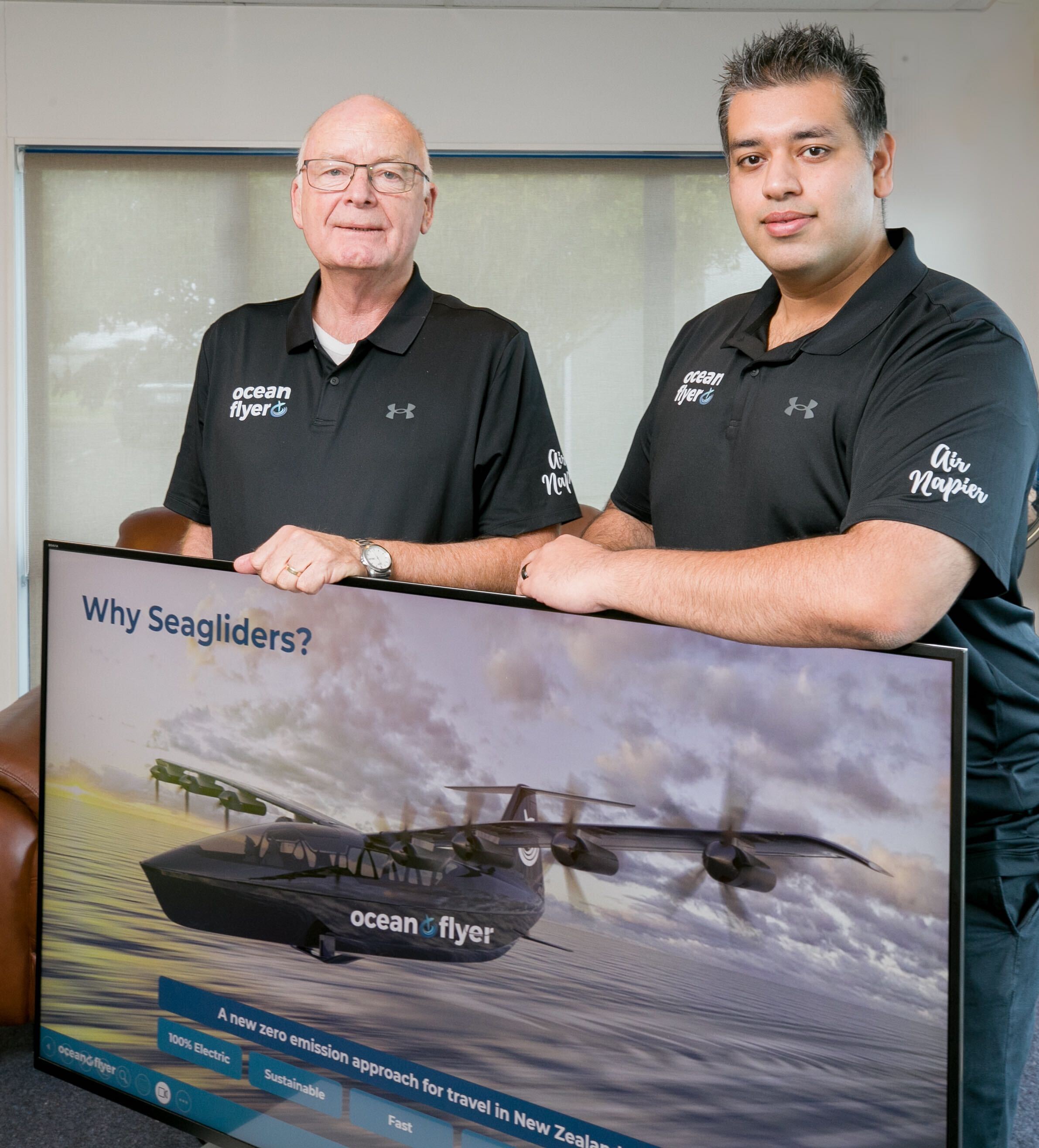 Ocean Flyer operations manager and Air Force veteran John Hamilton (left) and owner Shah Aslam with the new electric Seaglider aircraft on screen.  Photo / Warren Buckland