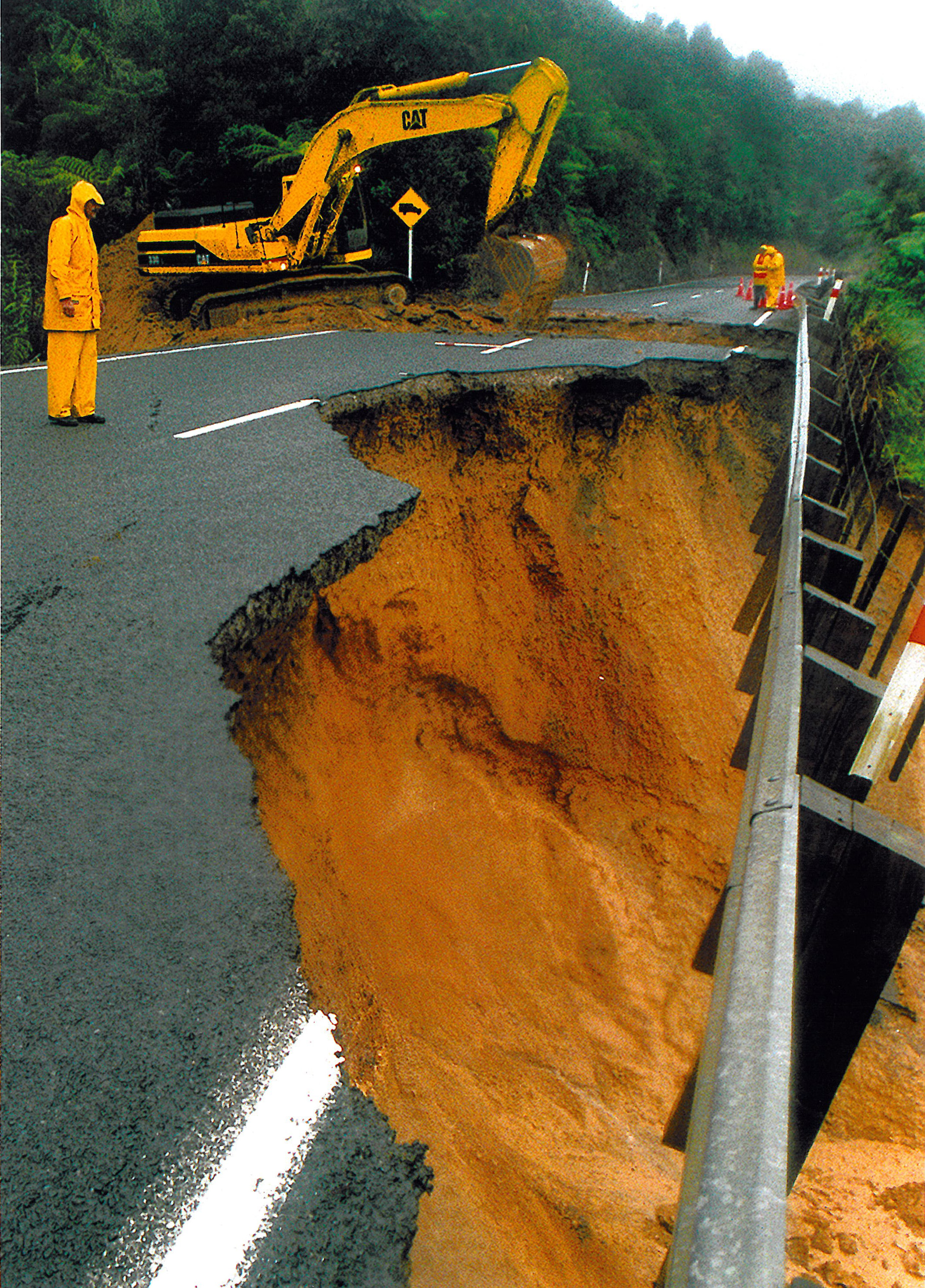 Workers inspect the remains of the section of State Highway 1 on the Brynderwyn Hills that was closed after a slip following Cyclone Fergus. Photo / NZ Herald