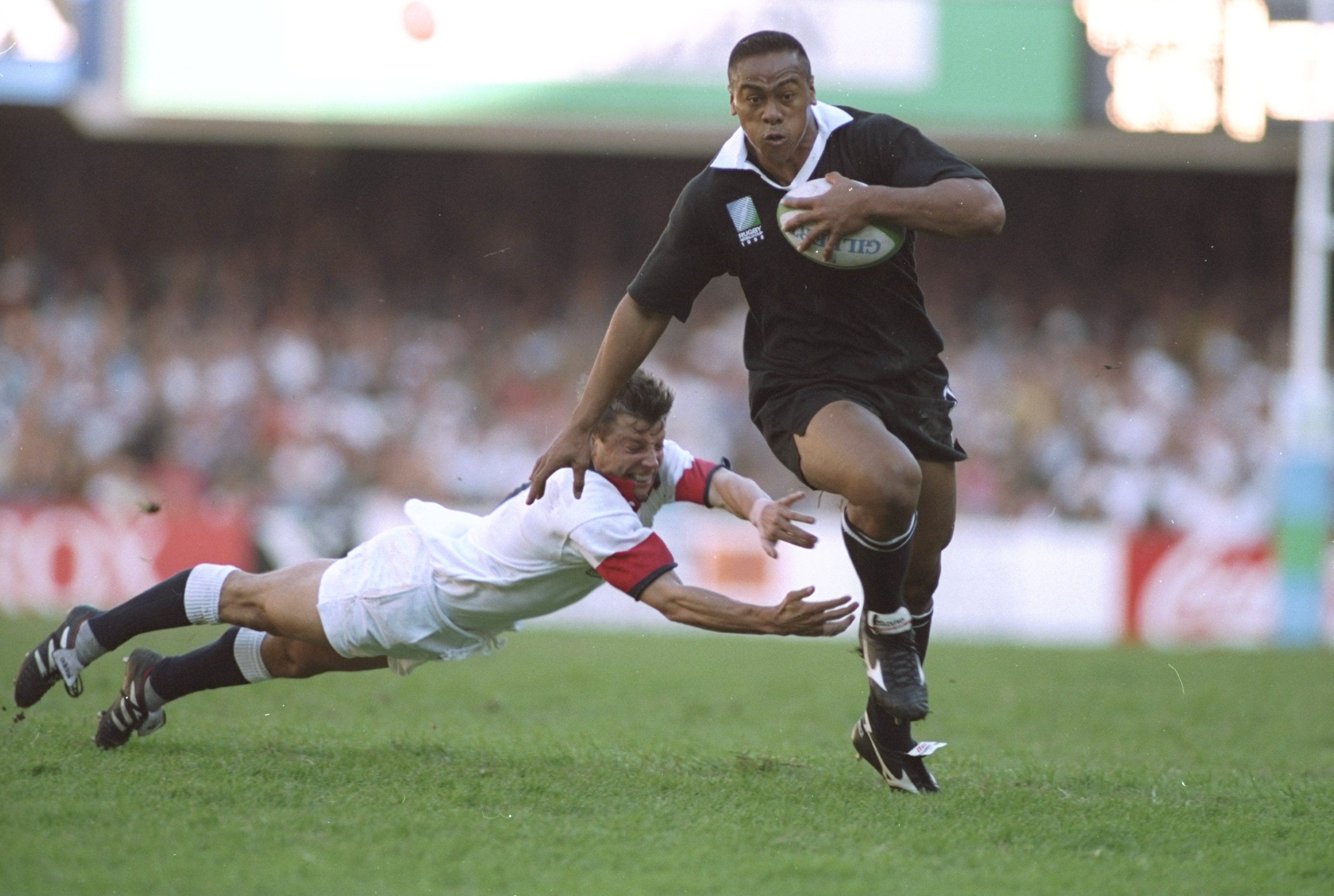 Jonah Lomu evades the diving tackle of Rob Andrew of England during the Rugby World Cup semifinal at the Newlands Stadium in Cape Town, South Africa in 1995. New Zealand won the match 45-29. Photo / Simon Bruty / Allsport