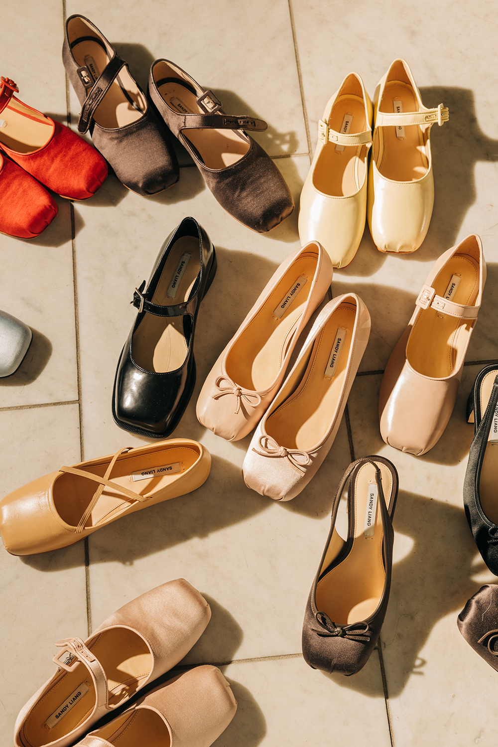Red and brown satin versions of the Mary Jane flat with a pointe toe that Sandy Liang introduced in 2022, top left, with other shoes she has designed, at her studio in New York. Photo / Jeenah Moon, The New York Times