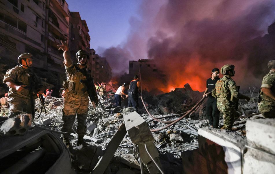 Lebanese army soldiers gather over the rubble of a levelled buildings as people flight the flames, following Israeli air strikes in the Haret Hreik neighbourhood of Beirut's southern suburbs on September 27, 2024. A source close to Hezbollah said the massive Israeli strikes on Beirut's southern suburbs flattened six buildings. (Photo by Ibrahim AMRO / AFP)