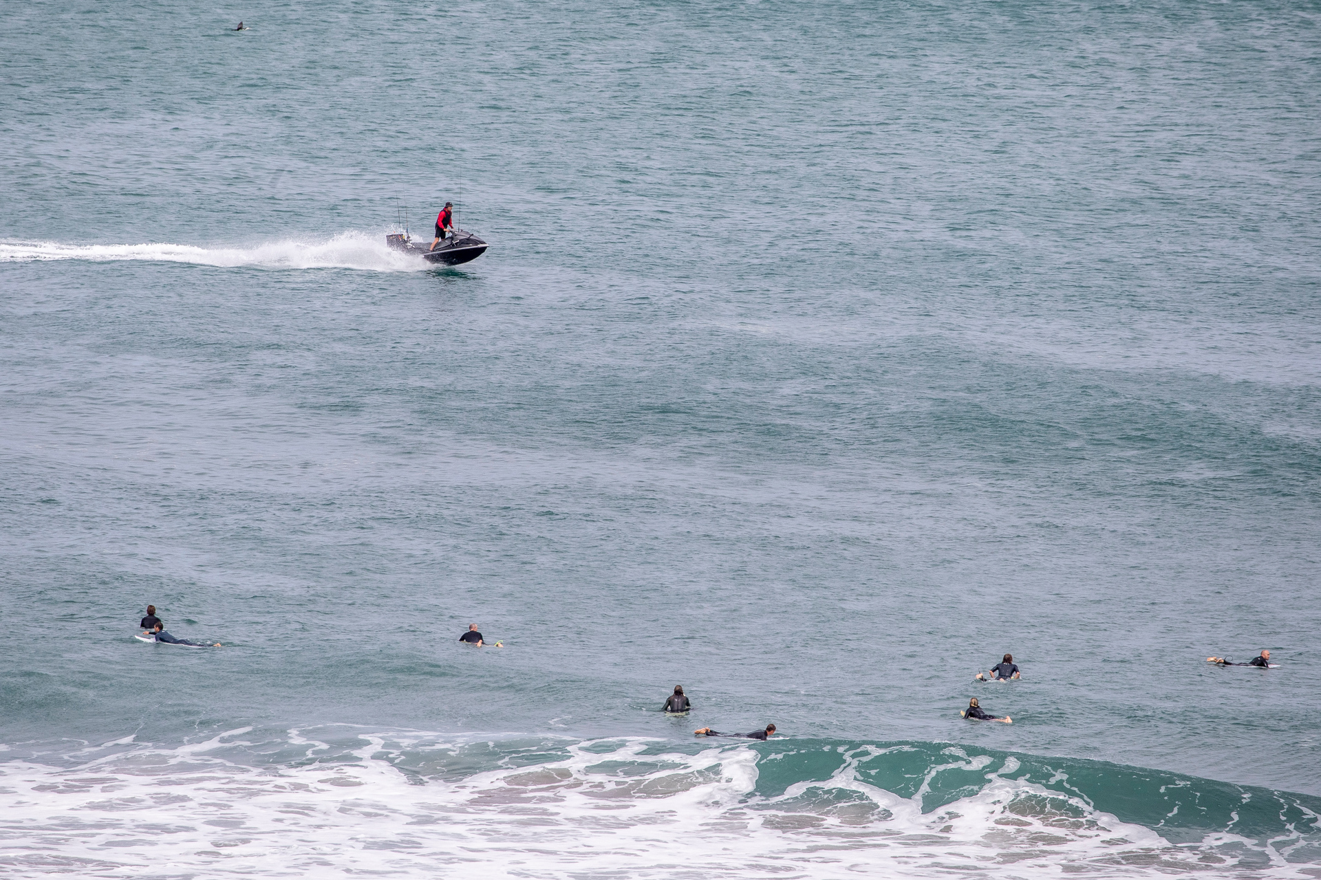 Jet ski fisherman and surfers at Muriwai Beach. Photo / Michael Craig