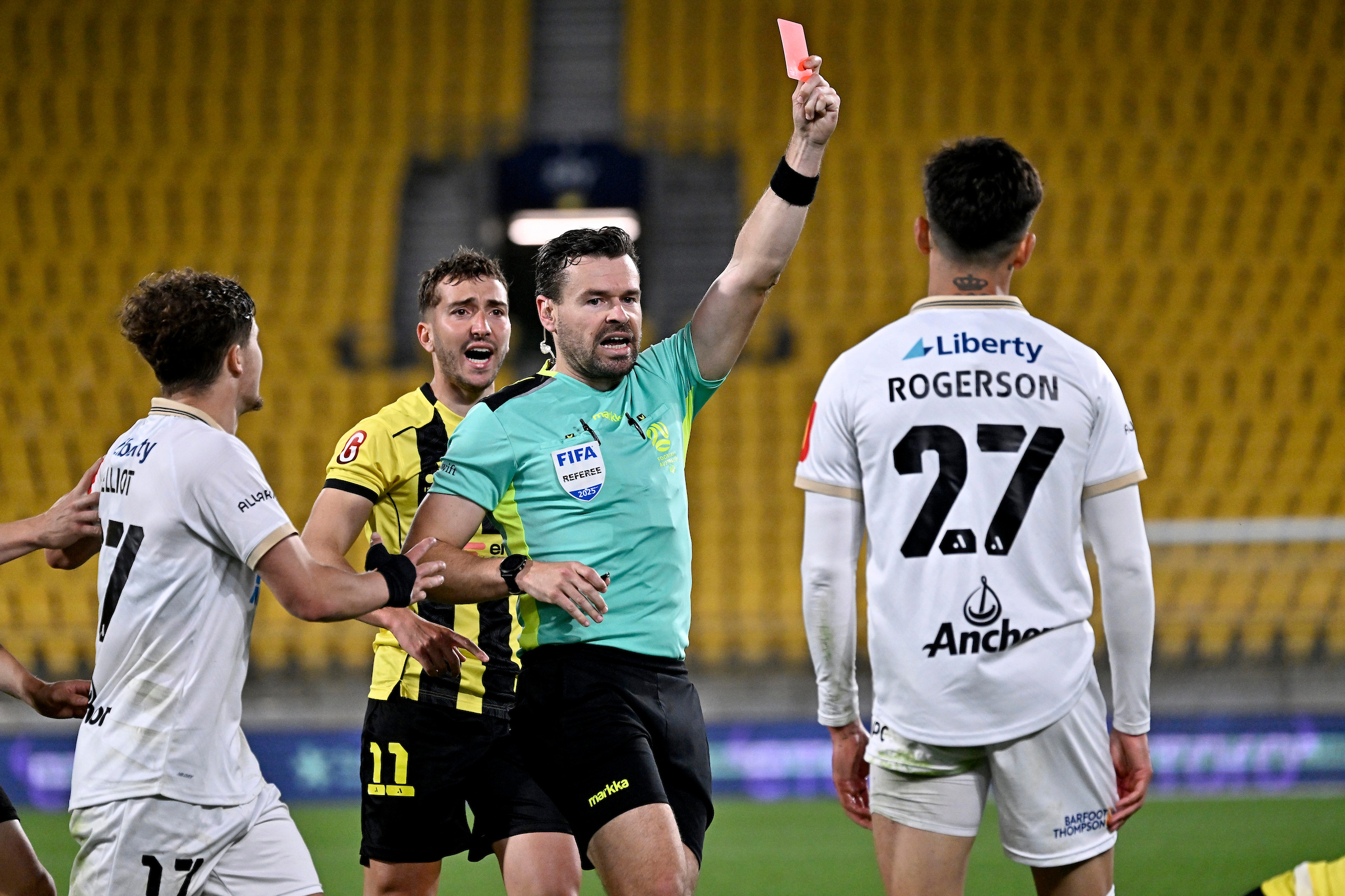 Referee Ben Abraham shows a red card to Auckland FC's Logan Rogerson.