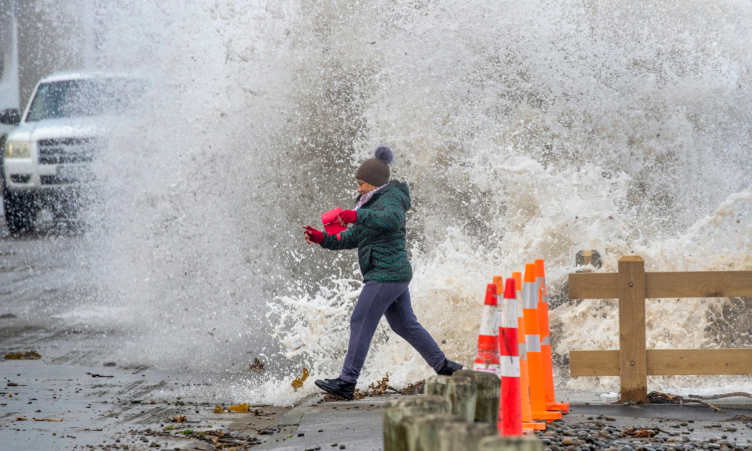 Owhiro Bay Parade resident Nyoman Wardani has to run for safety after being caught by surprise when a large swell crashed onto the seawall on Wellington's South coast. Photo / Mark Mitchell