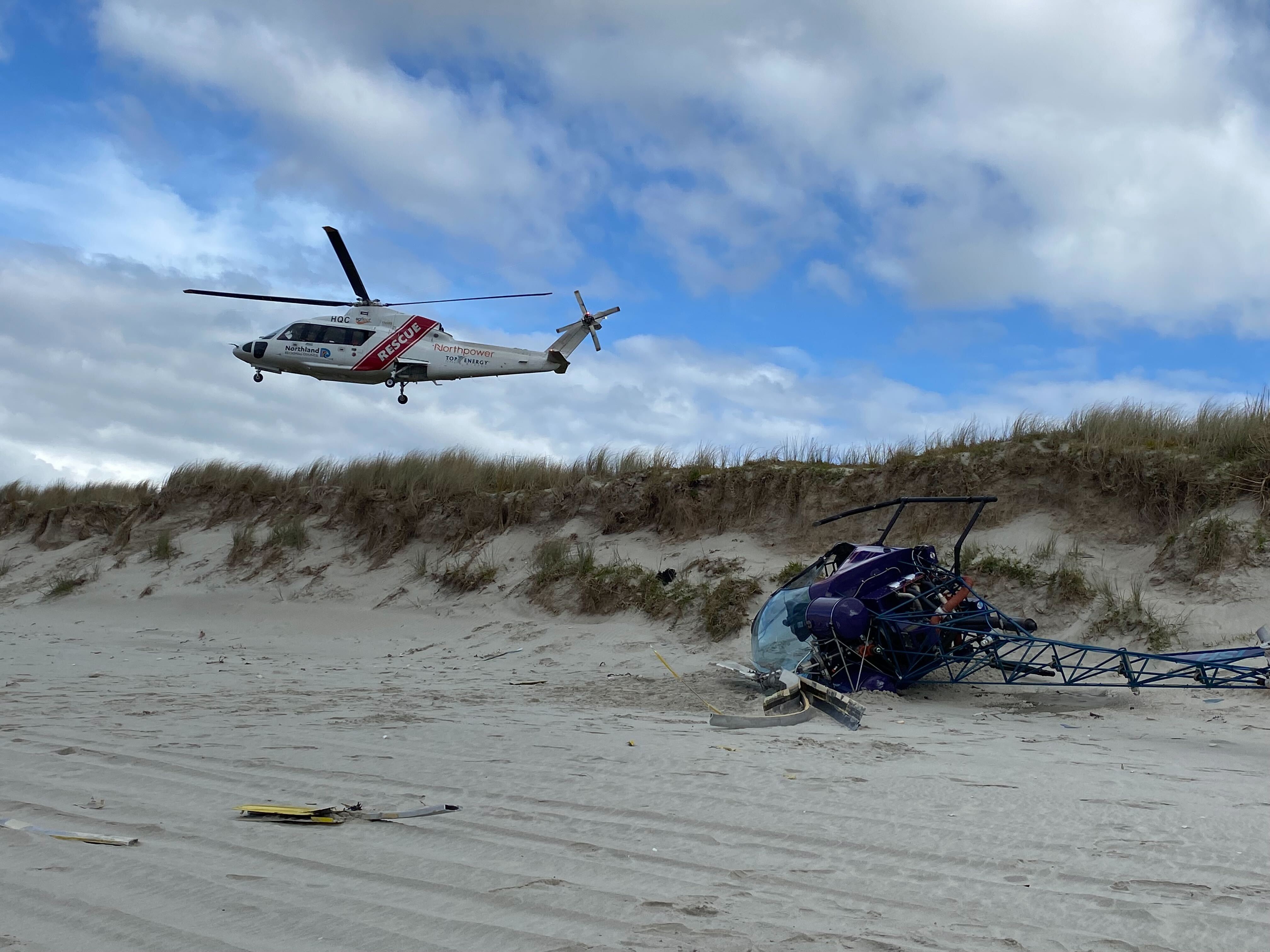 The Northland Emergency Services Trust helicopter leaves the scene of the helicopter crash on Uretiti Beach near Waipu. Photo / George Block
