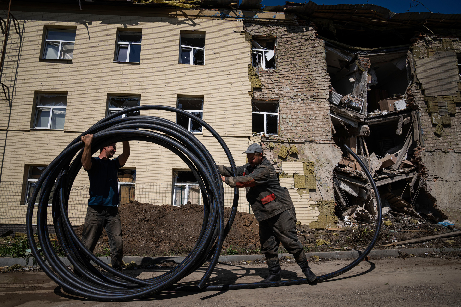 Municipal workers prepare a new tube to restore water supply in front of the building damaged by a Russian attack in Bahmut, Ukraine, on May 12. Photo / AP