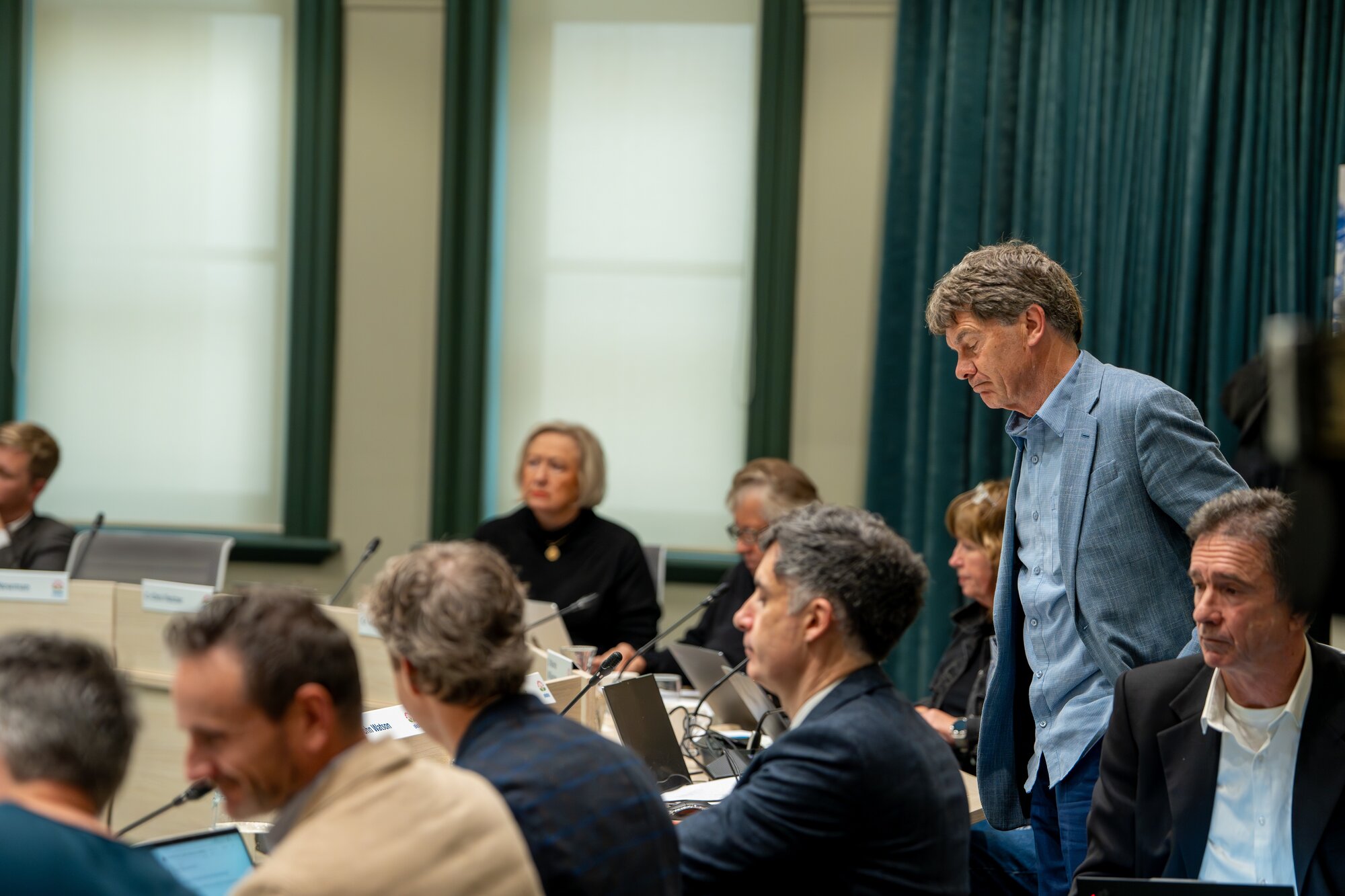 Wayne Walker (standing) with other councillors and officials during a break in the debate about new planning rules for housing across Auckland. Photo / Corey Fleming 