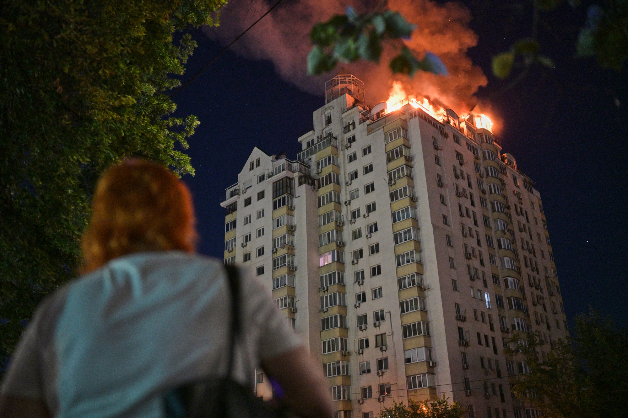 A woman looks at an apartment building burning after a Russian missile attack in Kyiv, Ukraine, Thursday, July 2, 2026. 