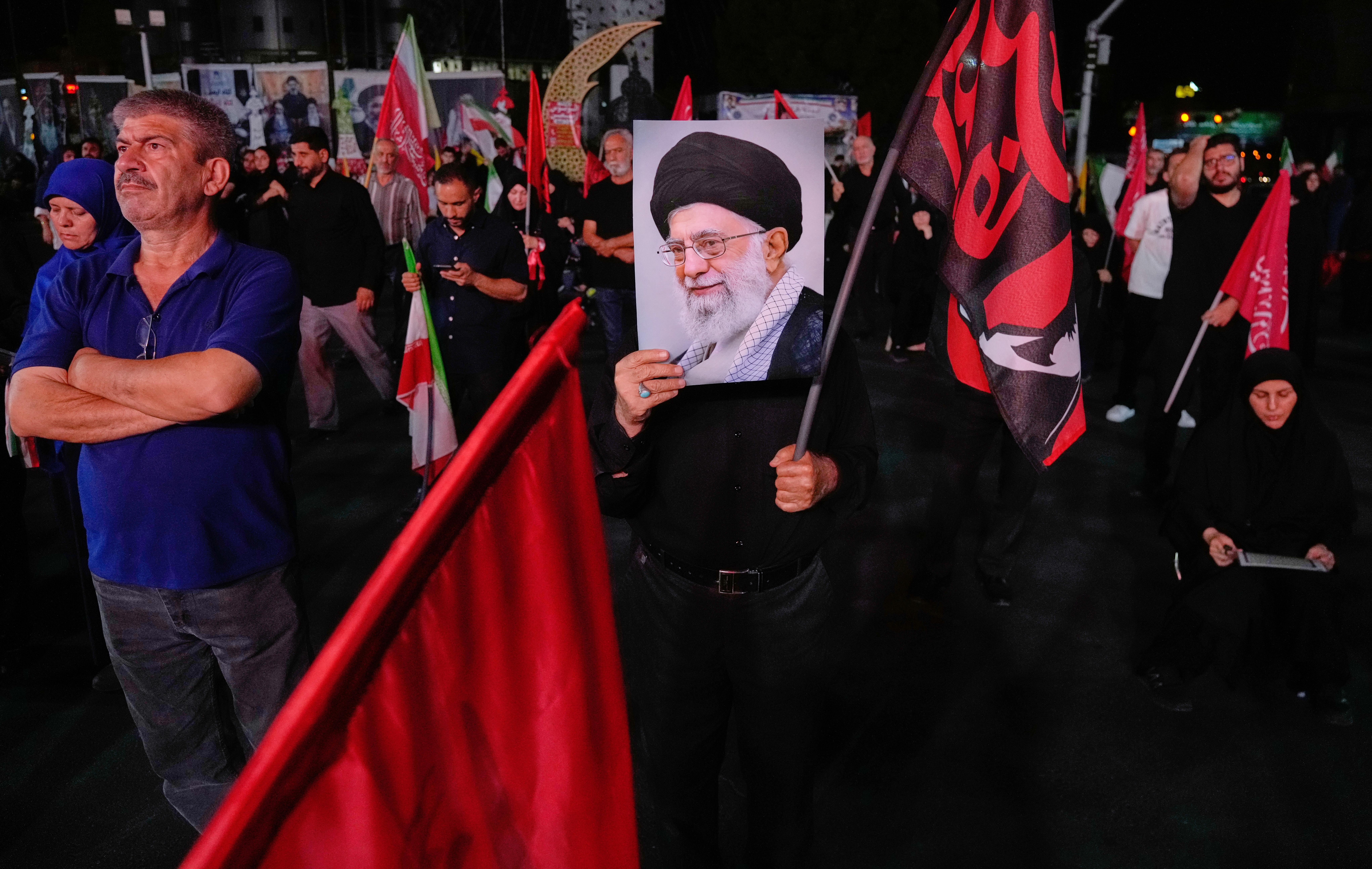 A man holds a poster of the late Iranian Supreme Leader Ayatollah Ali Khamenei in a gathering commemorating him at a square in Tehran.