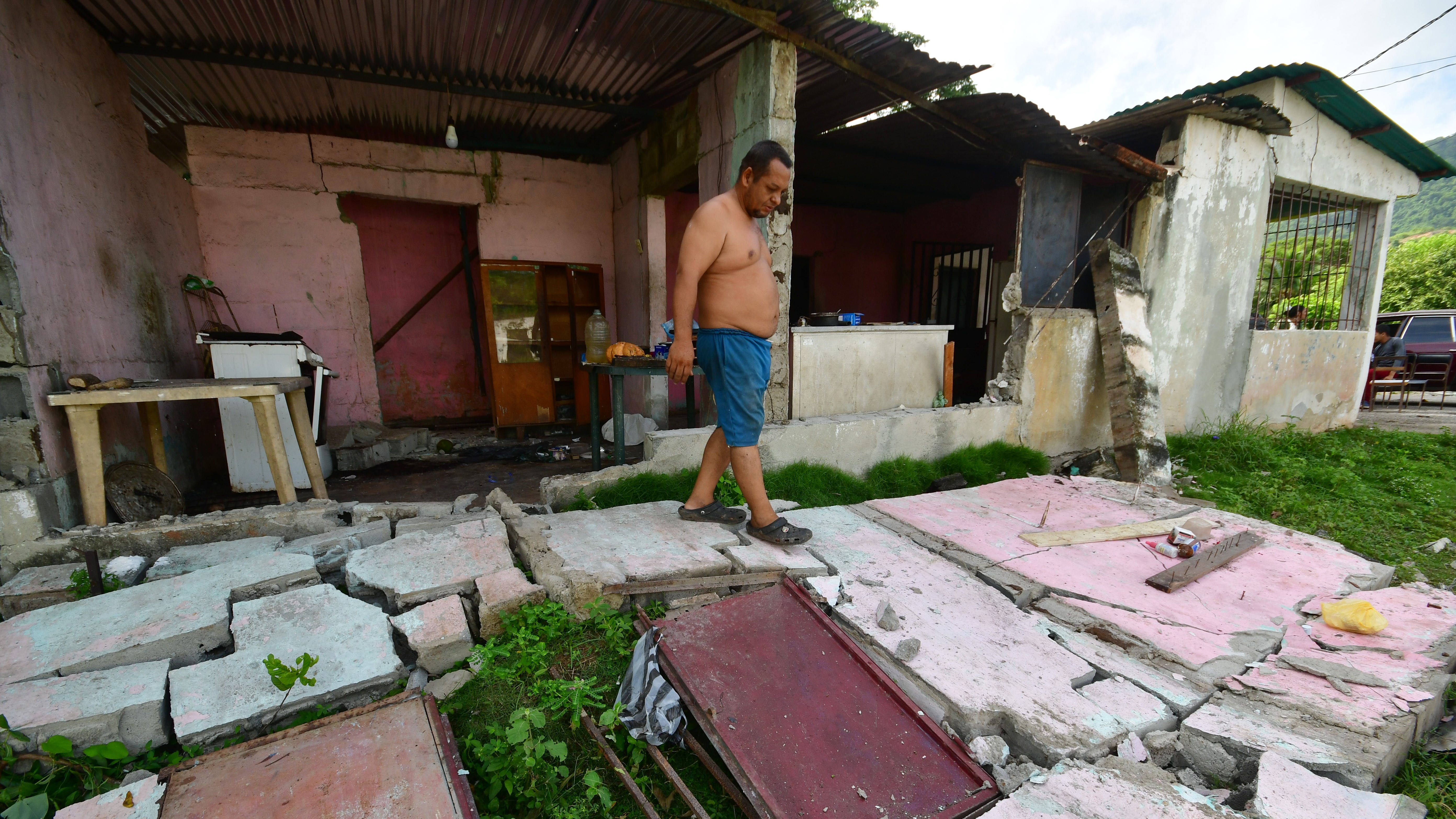 A man walks over the fallen walls of his home in Moron, near the epicenter of two earthquakes that struck Venezuela the day before.